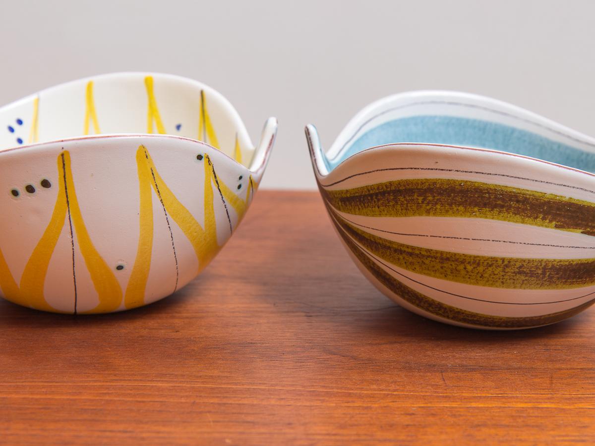Pair of original faience leaf bowls by Swedish designer Stig Lindberg for Gustavsberg. These playfully formed bowls have undulating, asymmetrical walls with hand painted features. The loose, geometric designs wrap around and inside the white glazed