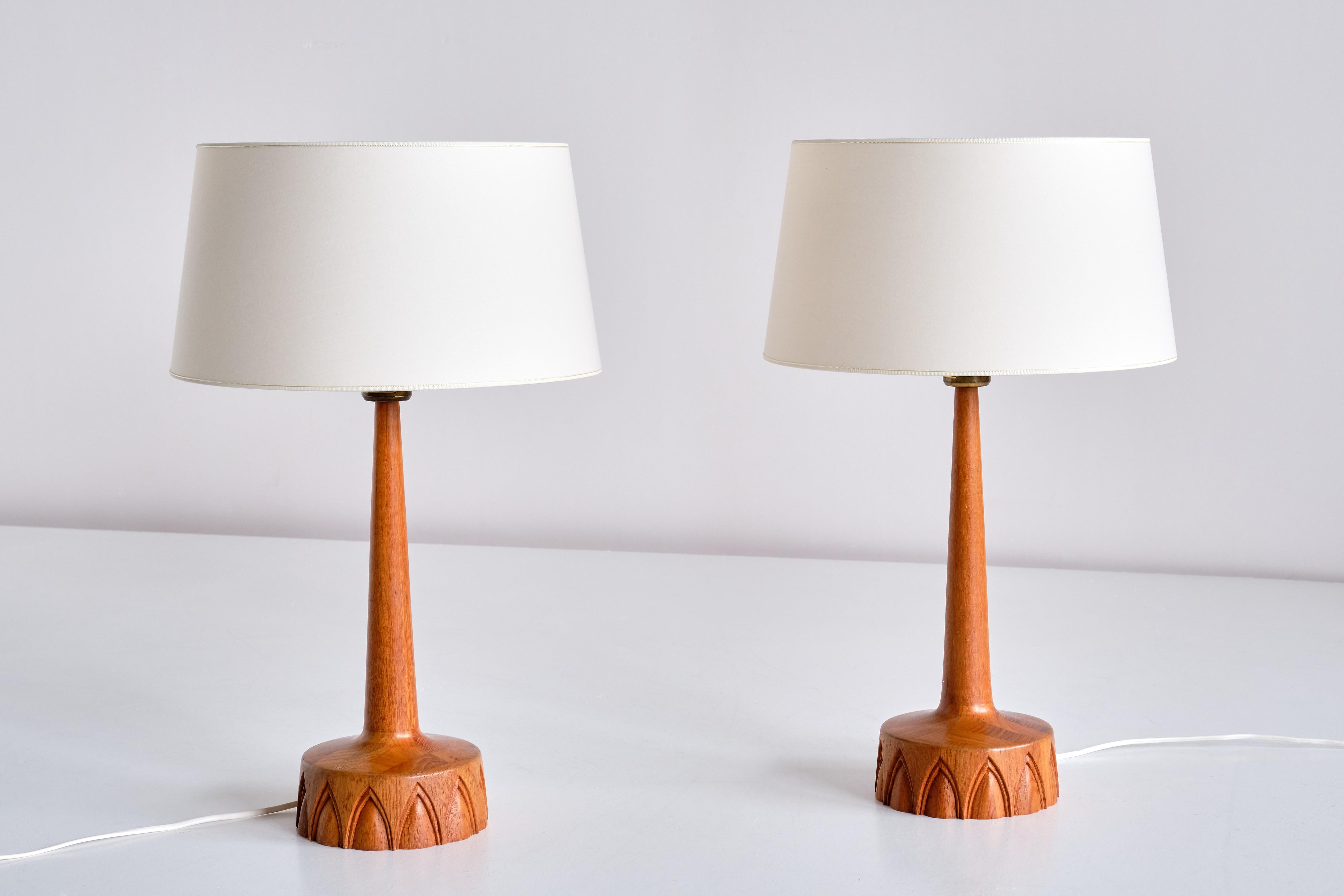 Cette élégante paire de lampes de table a été produite par AB Stilarmatur Tranås en Suède dans les années 1960. Fabriquées en bois de teck, les bases circulaires présentent un intéressant motif arqué sculpté à la main. L'interrupteur de la lumière