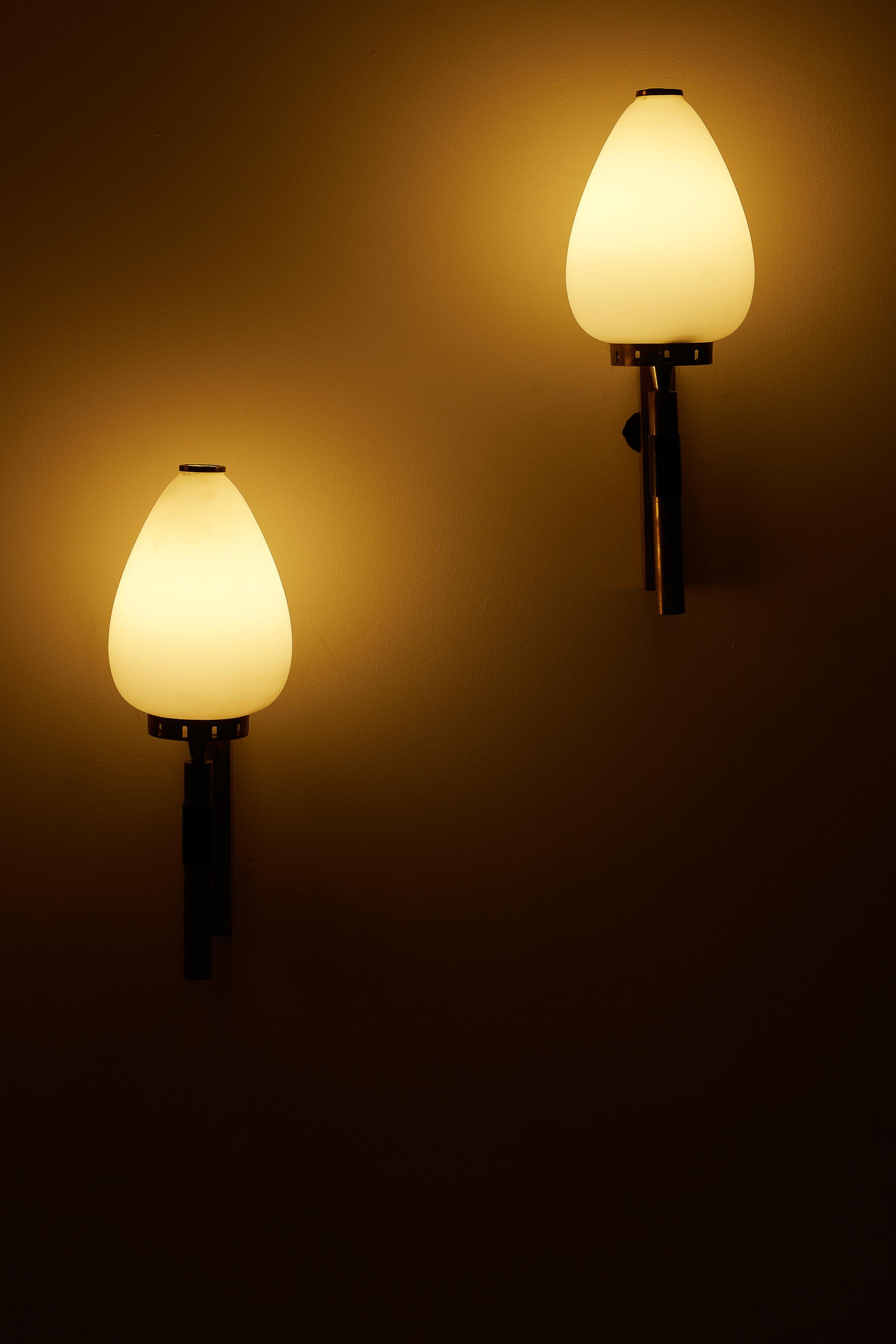 Pair of Stilnovo wall lamps dating from the 1950s-1960s. The lamps feature a brass structure and a white opaline glass diffuser. Stilnovo is an Italian design company that emerged after World War II, around the late 1940s. It is known for its modern