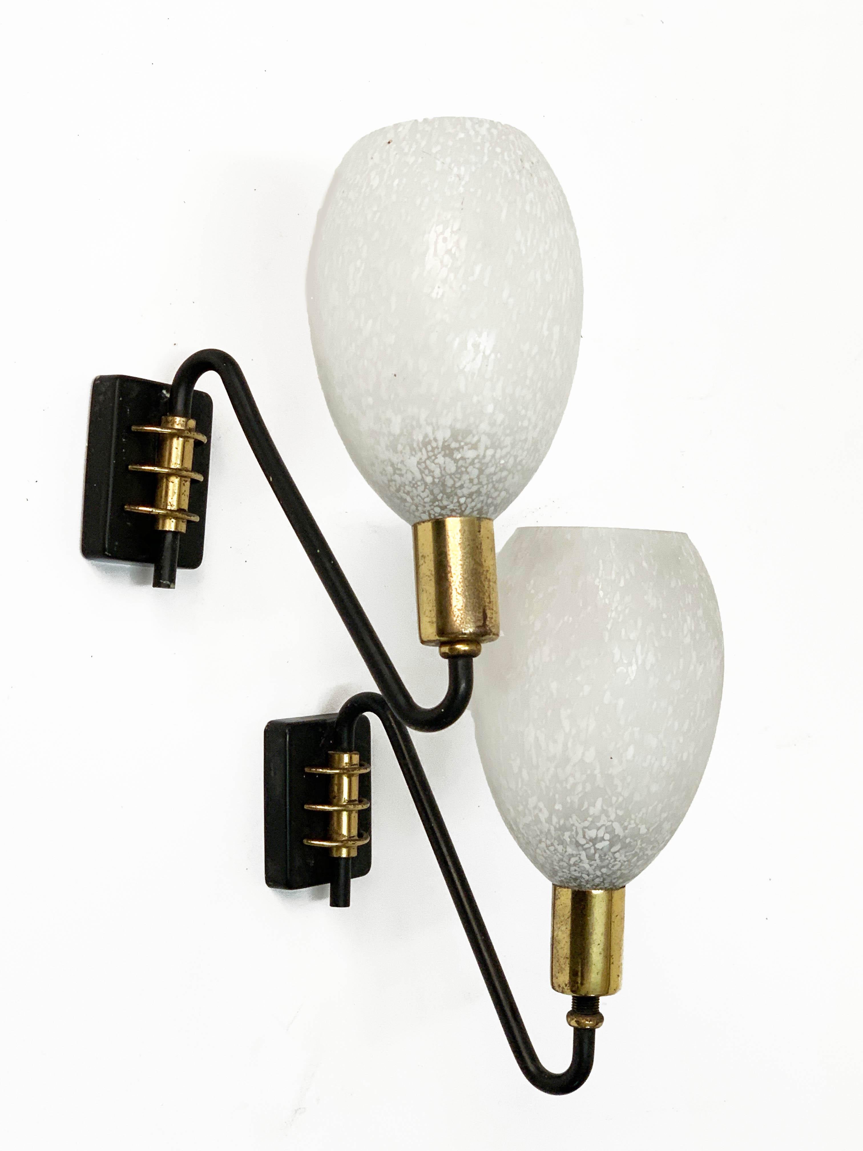 Pair of stunning midcentury sconces in brass and white Murano glass. These items were produced in Italy during the 1960s.

These items are a perfect mix of a spotted milky white Murano glass lampshade with a black enamelled metal and brass