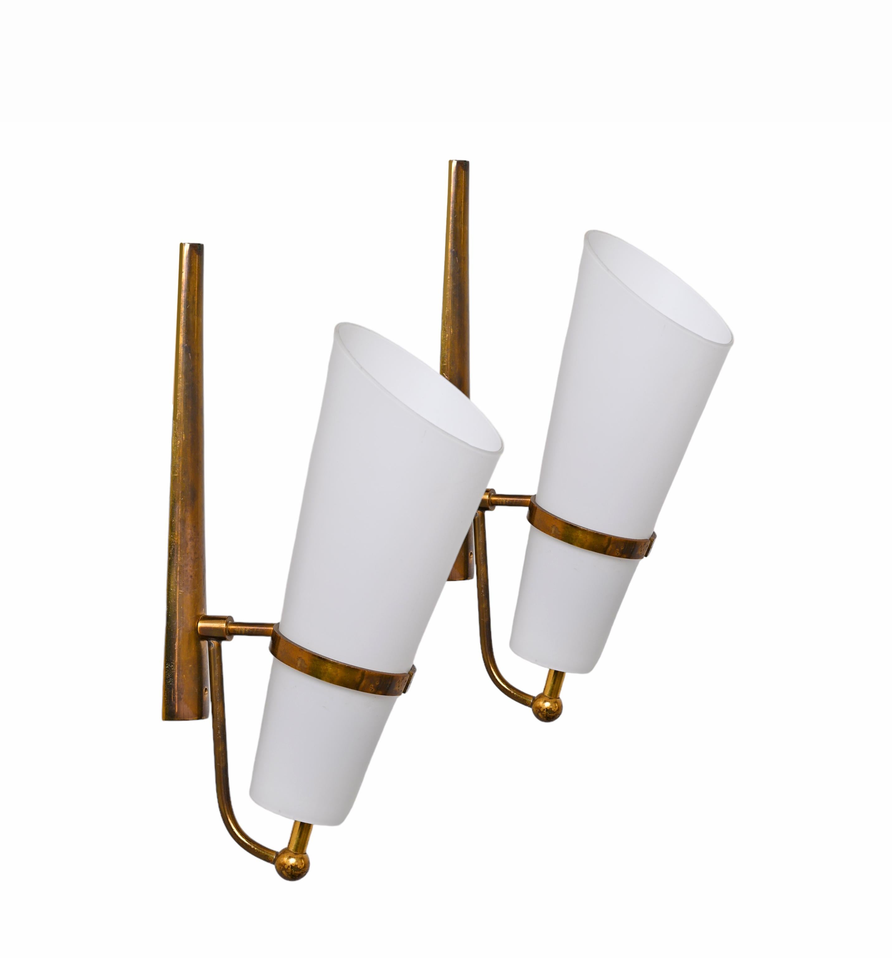 Fantastic pair of of opaline glass and brass sconces. These elegant wall lamps were designed in Italy in the 1950s and are attributed to Stilnovo. 

The sconces consist of a beautiful conic opaline glass and a brass structure, that has been kept