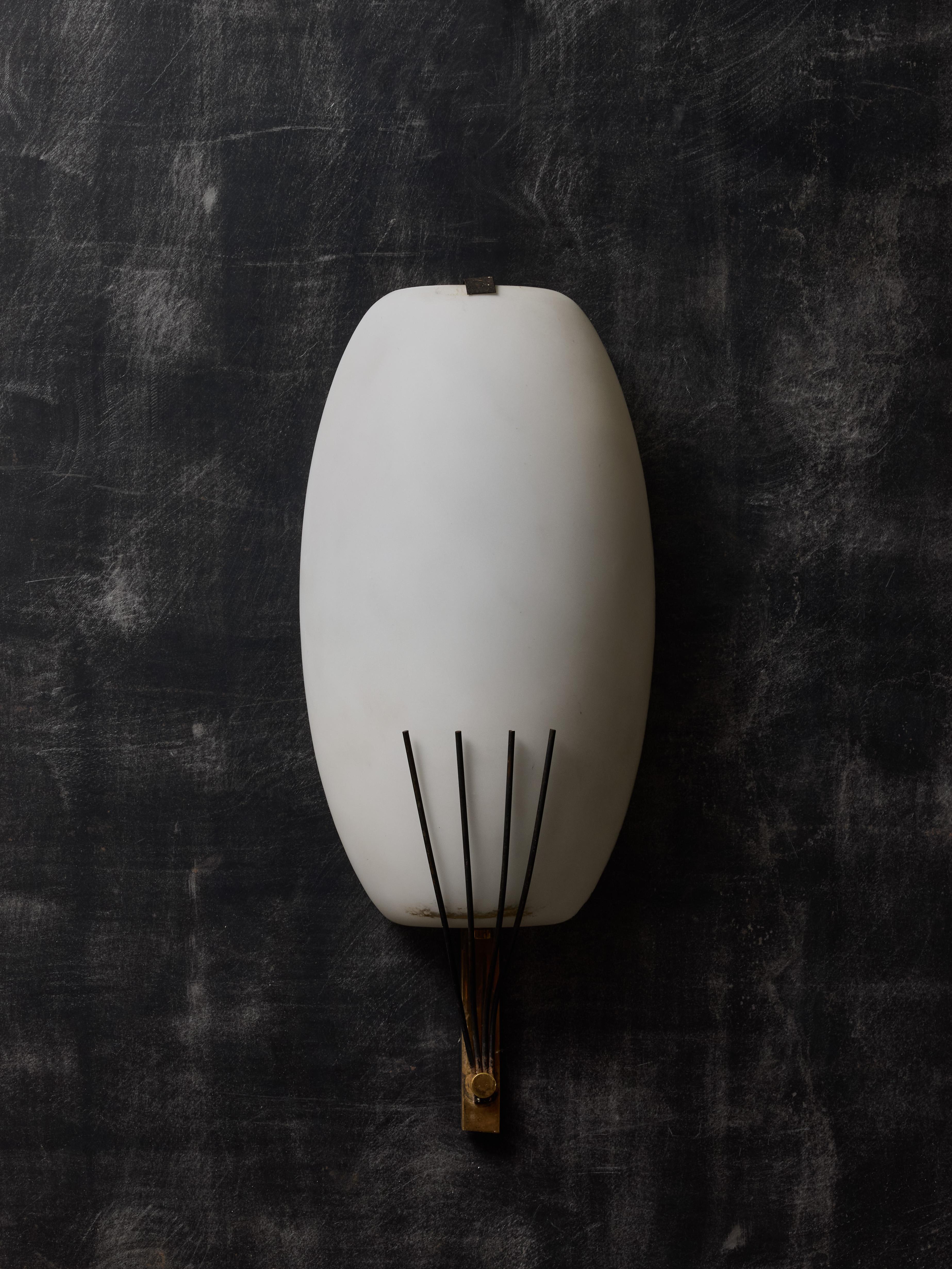 Pair of vintage Stilnovo wall sconces made of a shiny brass backplate, covered with a curved mat opaline glass shade hold in place by metal claws.

Stilnovo

Stilnovo is a prestigious Italian lighting manufacturer

Founded in 1946 in Milan by Bruno