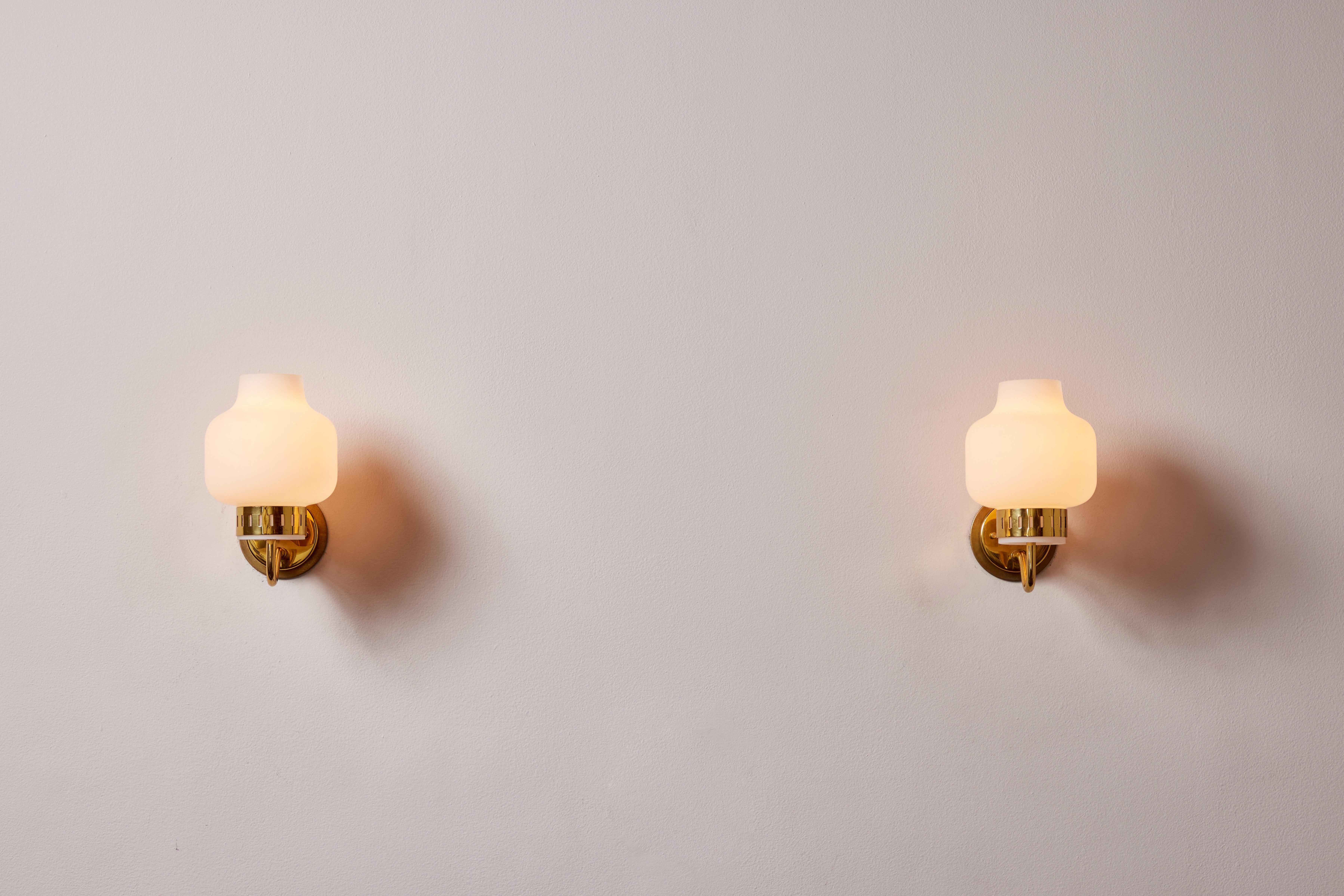 Pair of Stilnovo sconces. Manufactured in Italy, circa 1950's. Brushed satin glass diffusers, brass, custom brass backplates. Rewired for U.S. standards. We recommend one E27 60w maximum bulbs per fixture. Bulbs provided as a one time courtesy.