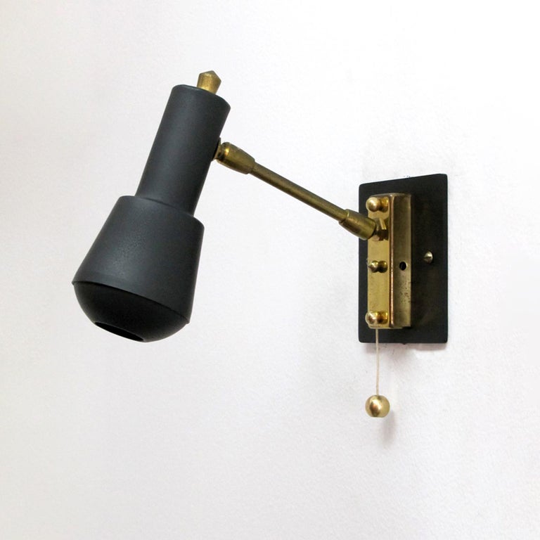 wonderful pair of articulate wall lights by Stilnovo, matte black bodies with visor on a Dual-joint brass arm with individual pull switch, custom brass back plate, wired for US standards, one E12 socket per fixture, max. wattage 40w per socket,
