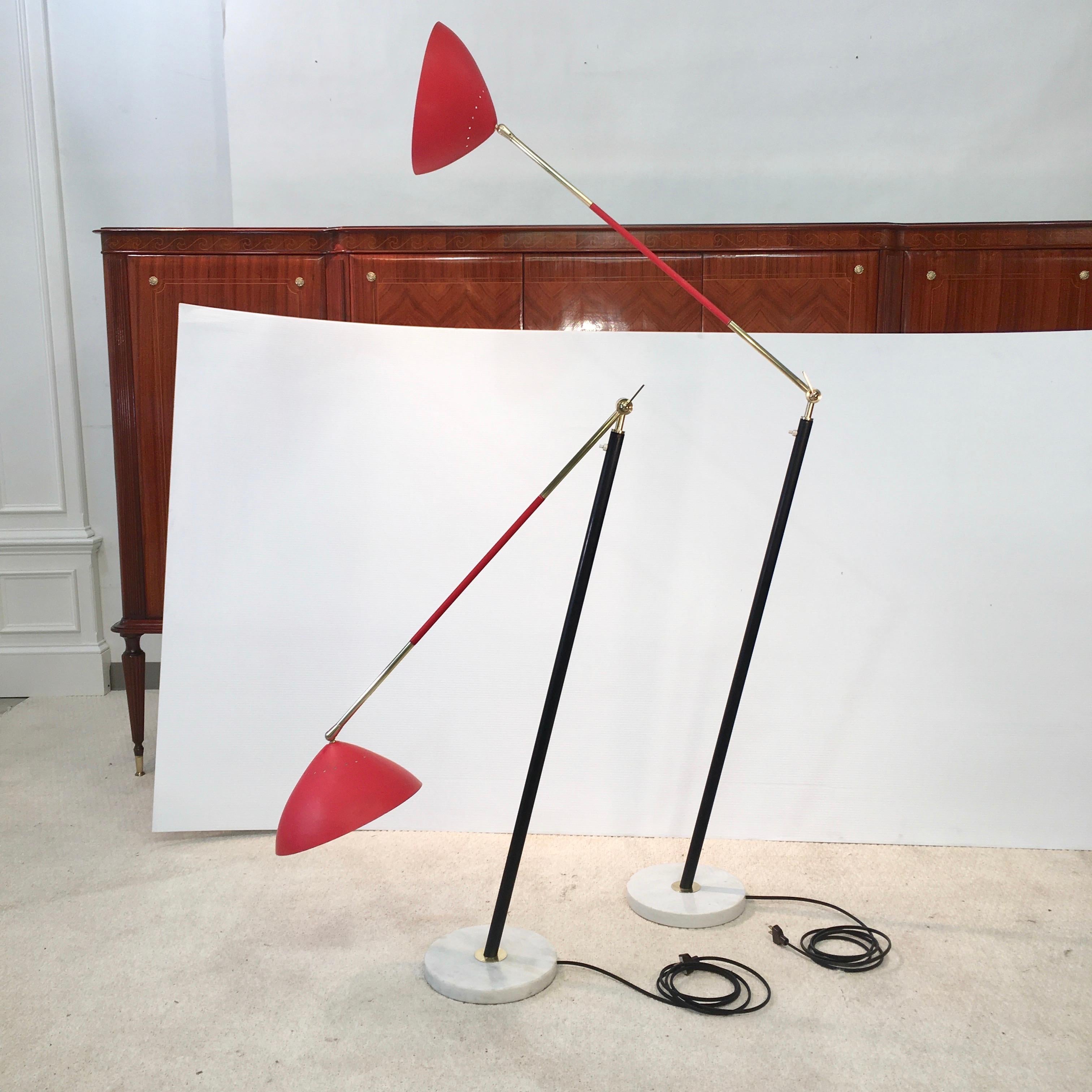 Matched pair of floor lamps by Stilux Milano designed by Oscar Torlasco with red shades, black enameled metal stem, brass arms and mounts. Articulating stem and shade with a white round marble base. Push button switch on stem. Iconic and playfully
