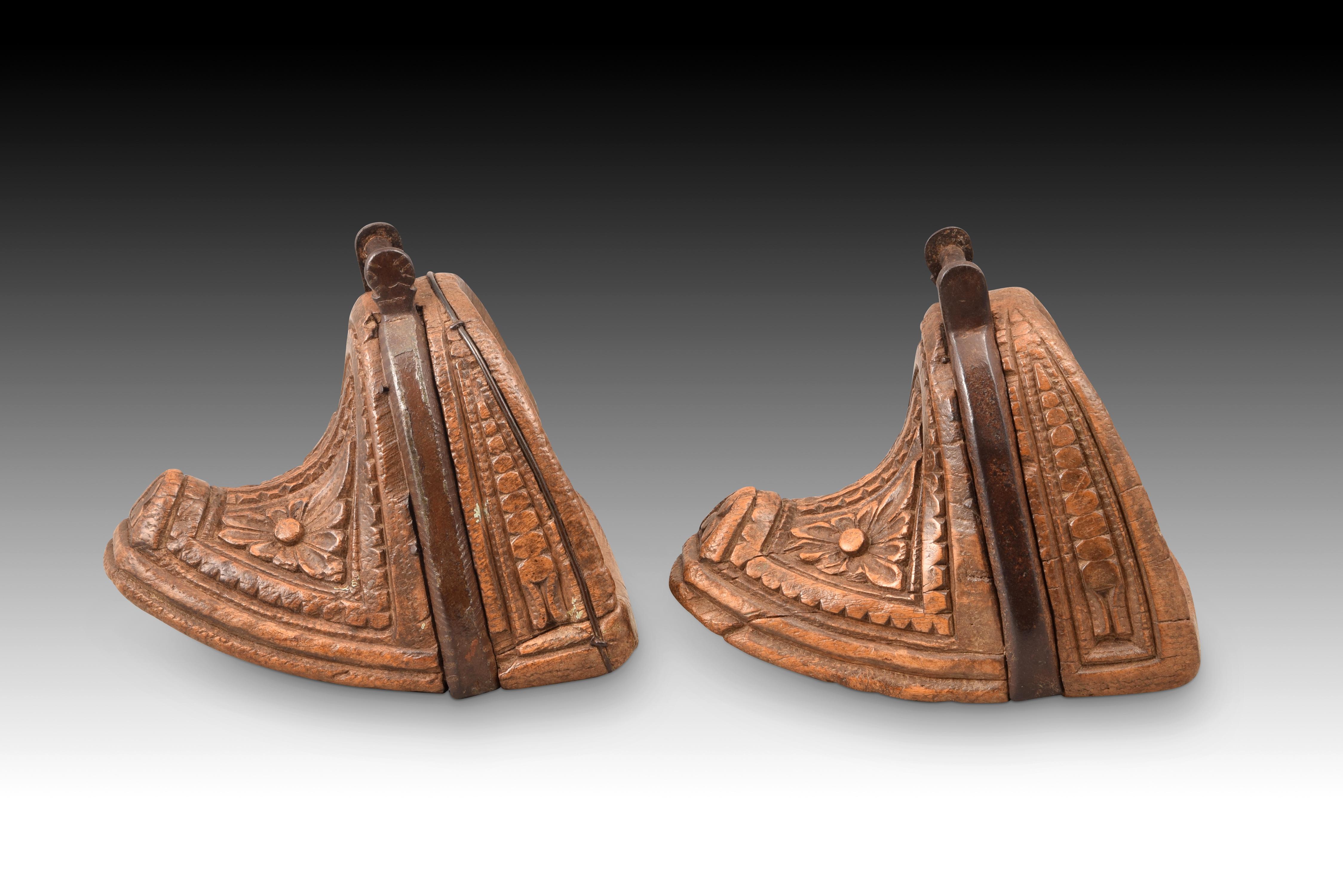 Ein Paar Steigbügel. Geschnitztes Holz, Eisen. Chile, 18. Jahrhundert. 
Paar Steigbügel, bestehend aus einem geschnitzten Holzblock, der auf der Vorderseite die Form eines Halbmondes hat und auf der Außenseite mit geometrischen und pflanzlichen