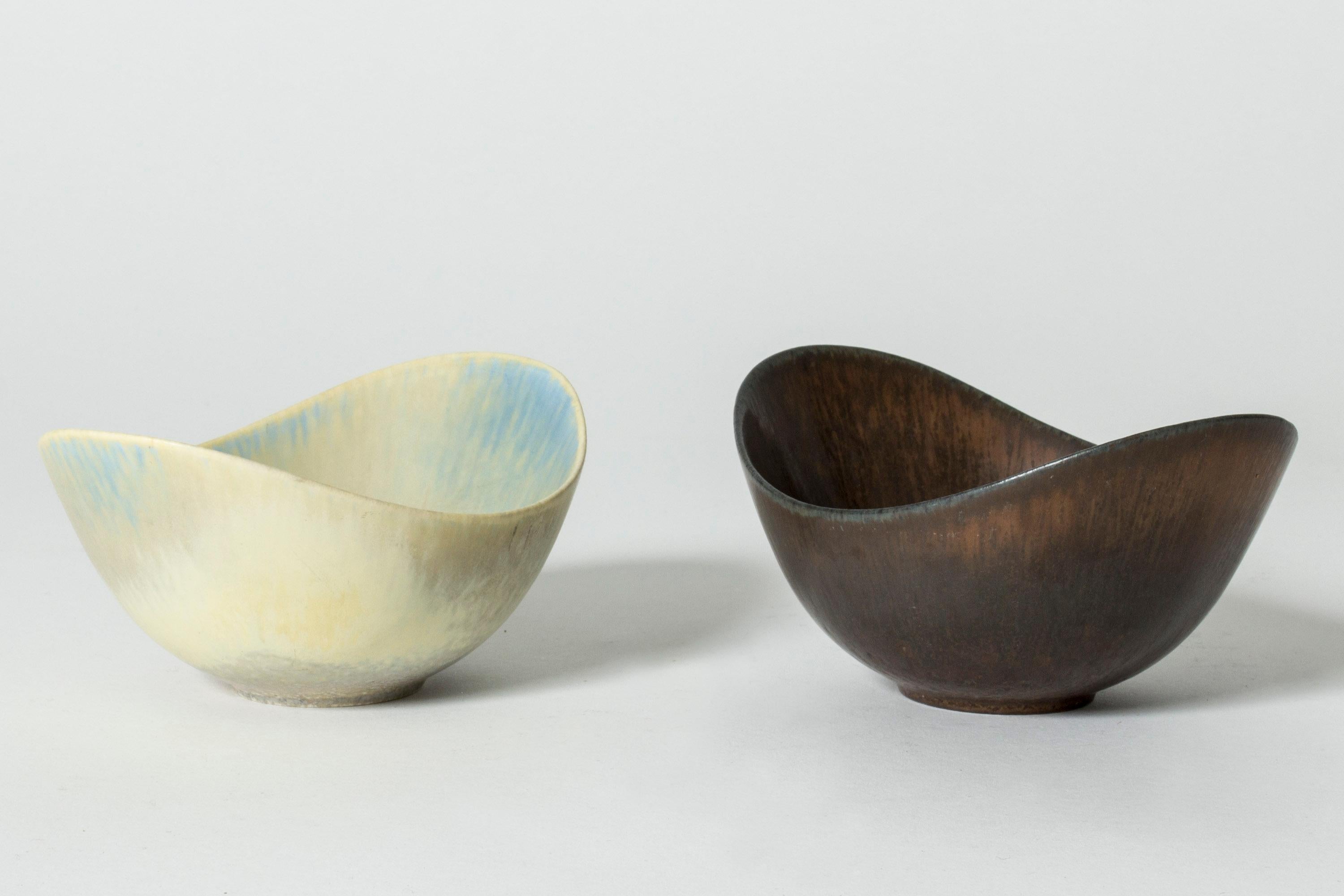 Pair of stoneware bowls by Gunnar Nylund, of the appealing “ARO” model. Streamlined, oval form with plunging sides. One with rich brown glaze and the other with eggshell and blue glaze.