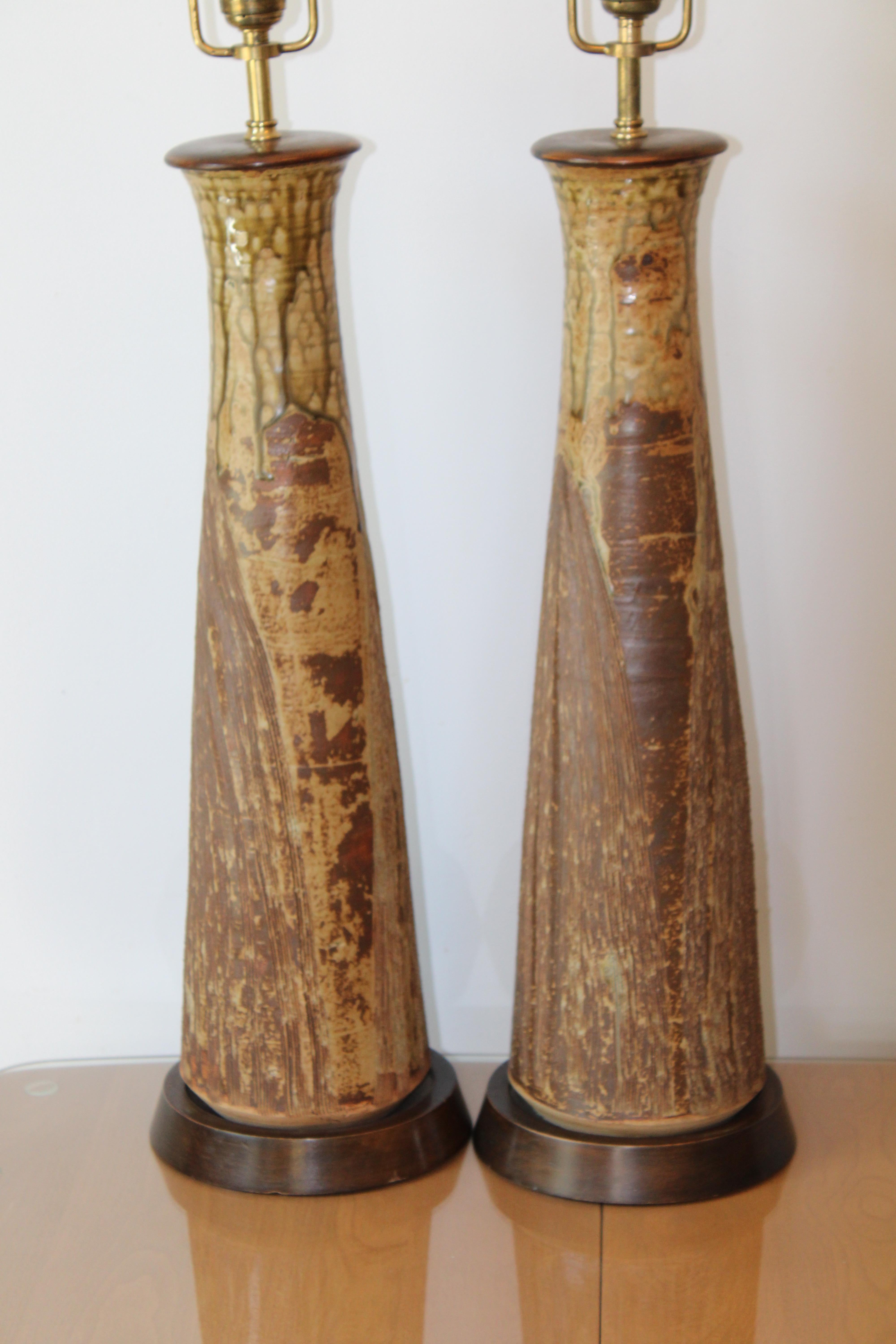 Pair of all hand thrown stoneware lamps with heavily incised surfaces and olive green drip glaze. Each lamp measures about 25