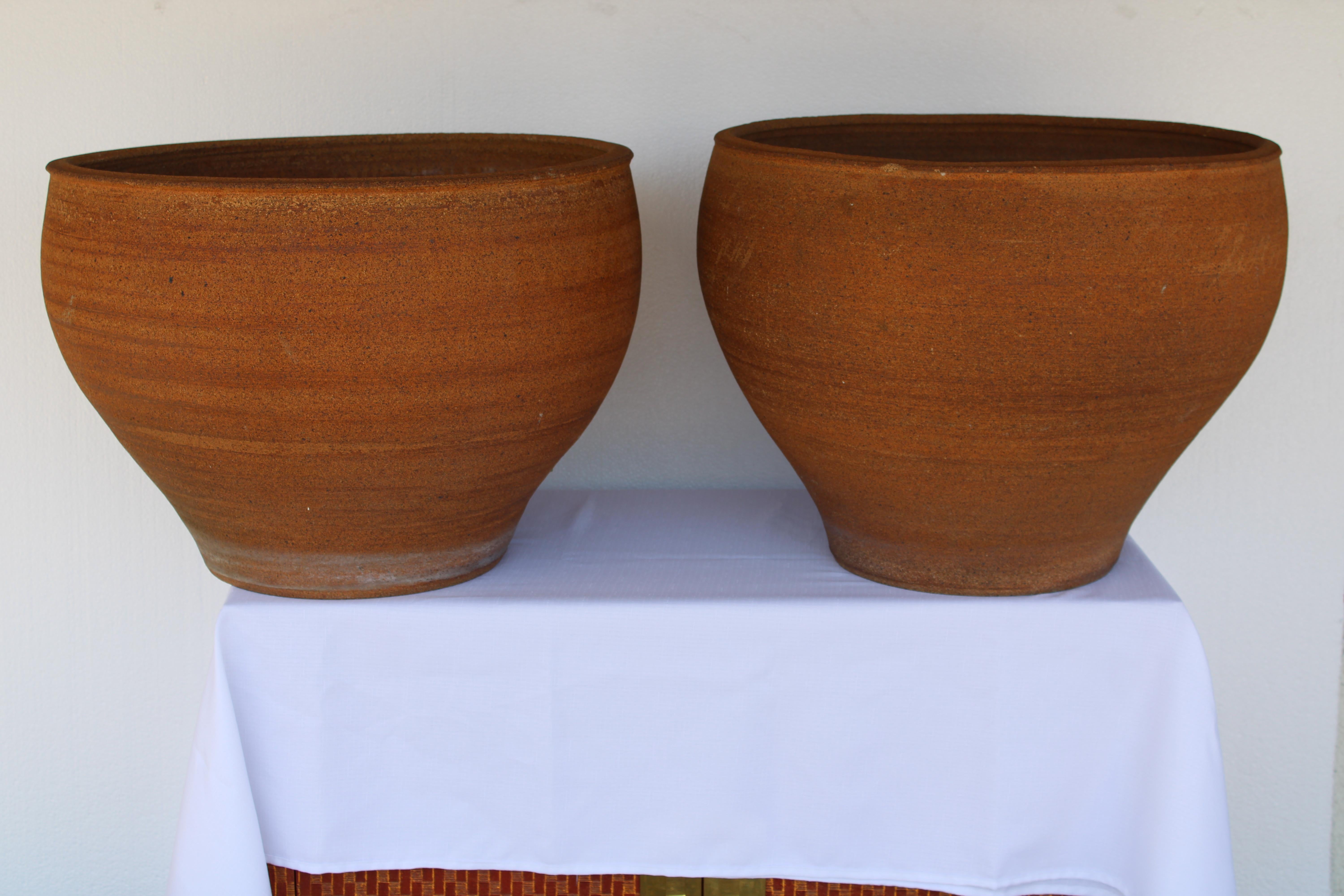Pair of stoneware planters by David Cressey. These are hand thrown and were probably a custom order. These stoneware planters have an unglazed interior as well as an unglazed natural warm brown clay exterior with the iconic 