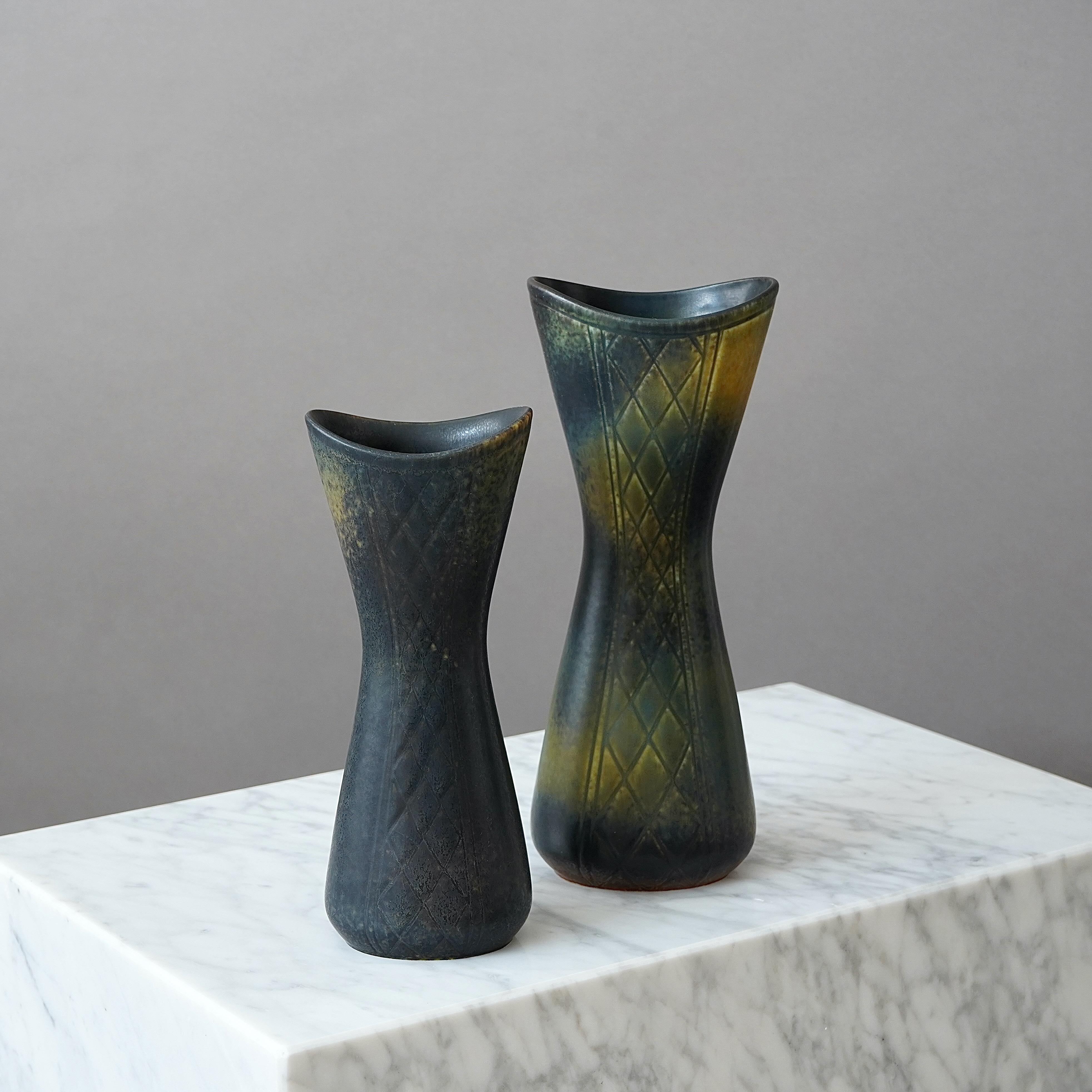 A pair of beautiful stoneware vases with amazing glaze and different incised patterns on each side.
Designed by Gunnar Nylund for Rorstrand, Sweden, 1950s.  

Excellent condition. Incised signature 