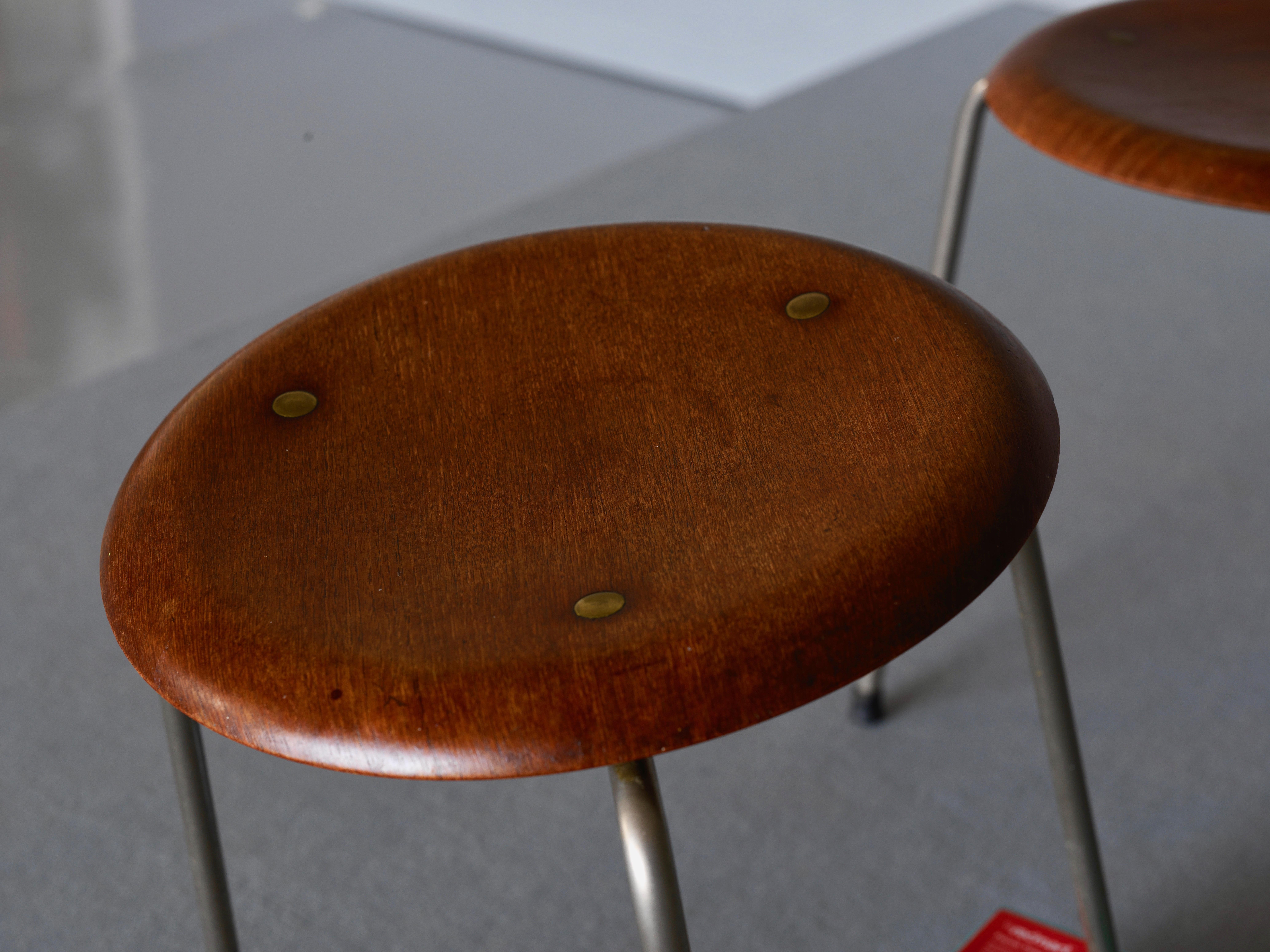 A pair of stools by Arne Jacobsen for Fritz Hansen, model DOT. They have a teak seat with a chrome plated frame. Original label “FH Denmark” remains.
Measures: H 46 D 33.
   