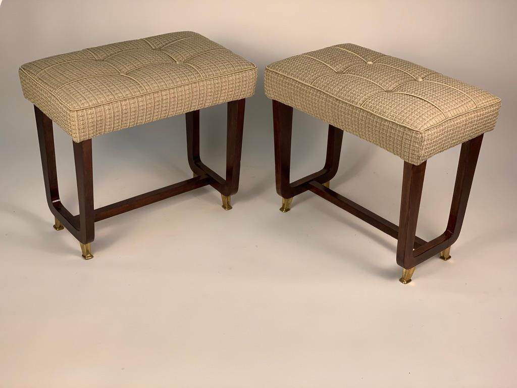 Pair of Italian wooden stools from 1950s. The seat are padded and upholstered with new fabric. Legs are connected by a crossbar and the four feet are in cast brass.