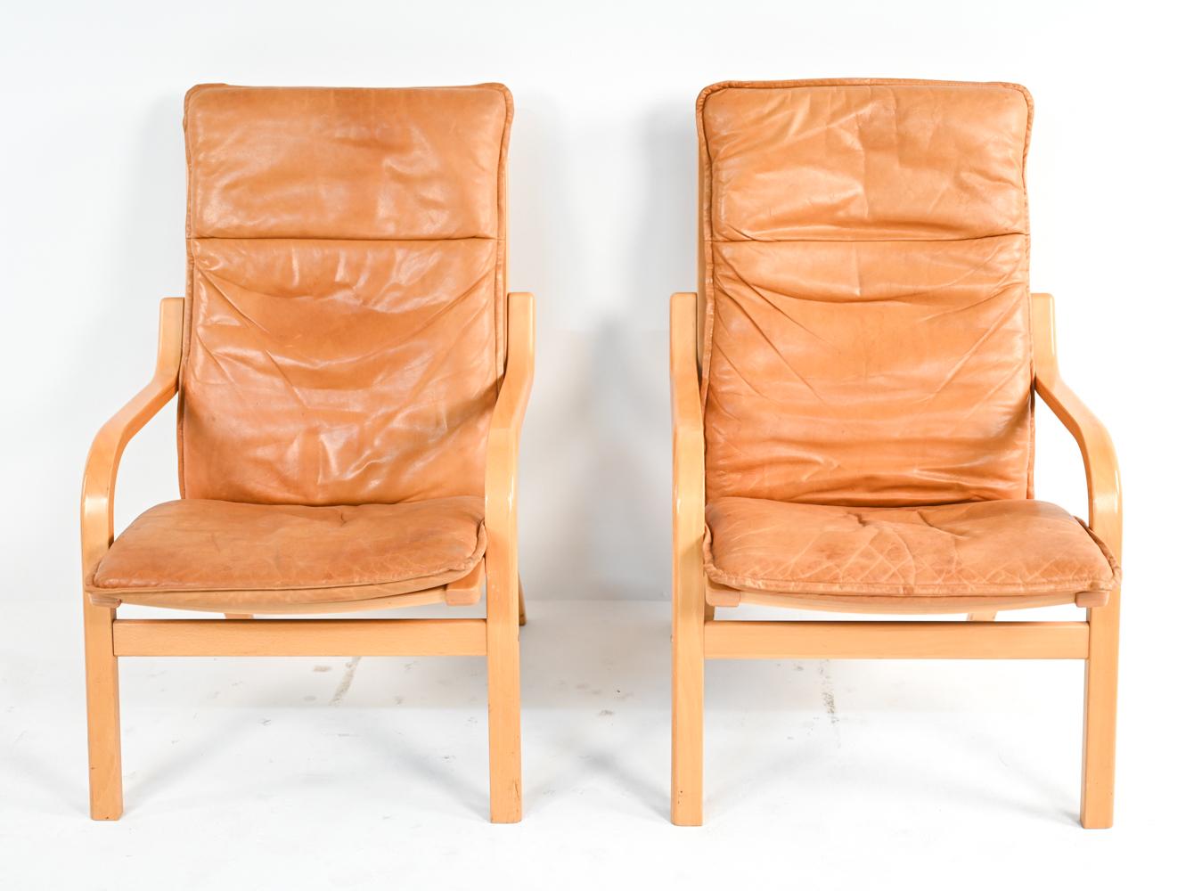 A stylish pair of Scandinavian modern highback model MH 101 lounge chairs by Mogens Hansen, produced by Stouby. Featuring sleek bentwood frames in blonde beech and handsomely patinated cognac leather cushions. These chairs are a fabulous example of