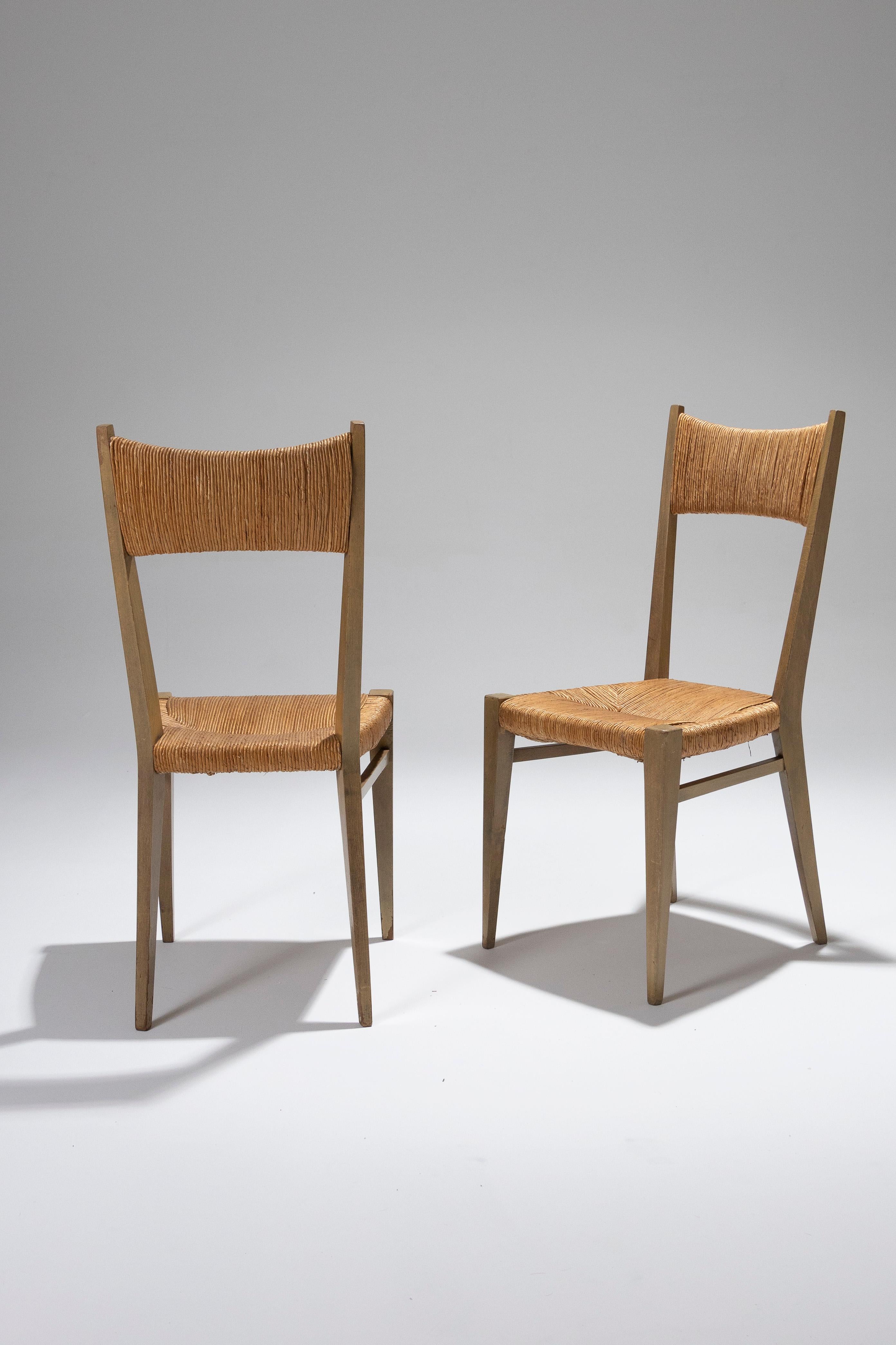 Elegant pair of chairs by Geneviève Pons, designed in the 1950s, blending Scandinavian influences with rustic charm. The tapered oak frame highlights a woven straw seat and backrest, giving these pieces a light and sophisticated look. The sleek