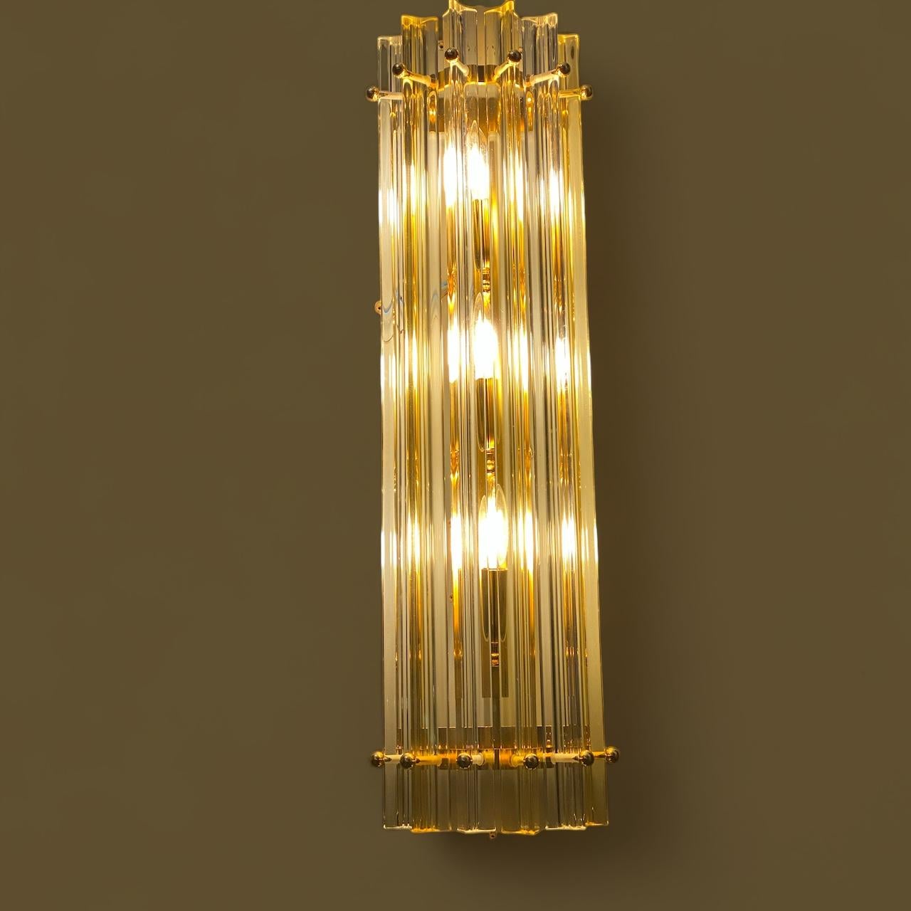 Feines Paar  bernsteinfarbener und klarer Tryi  Murano-Wandleuchter von einem  Prisma in Murano-Kristall mit goldenem Metallrahmen.

Glühbirnen: 2 Glühbirnen für jede Applique ( E 14 Dimension nicht in diesem Verkauf) Auf Anfrage können wir die
