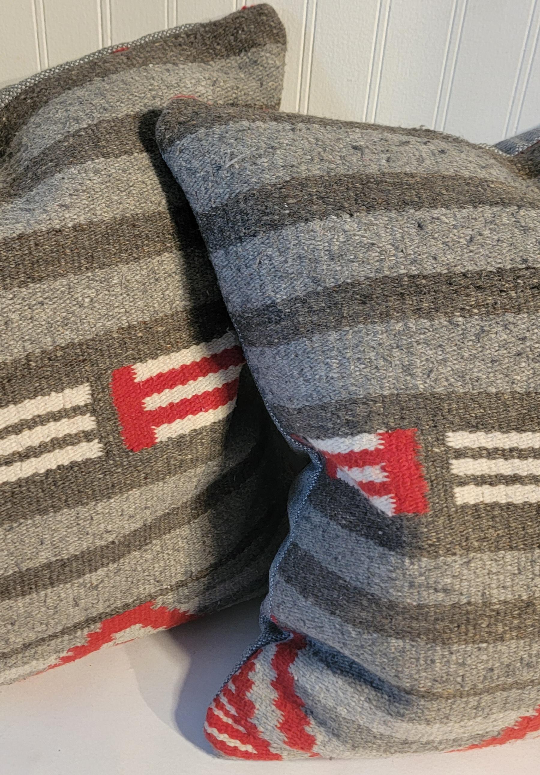 Coppia di cuscini di tessitura indiana Navajo grigi e rossi che assomigliano a una tessitura di terza fase. Il supporto è in cotone grigio.