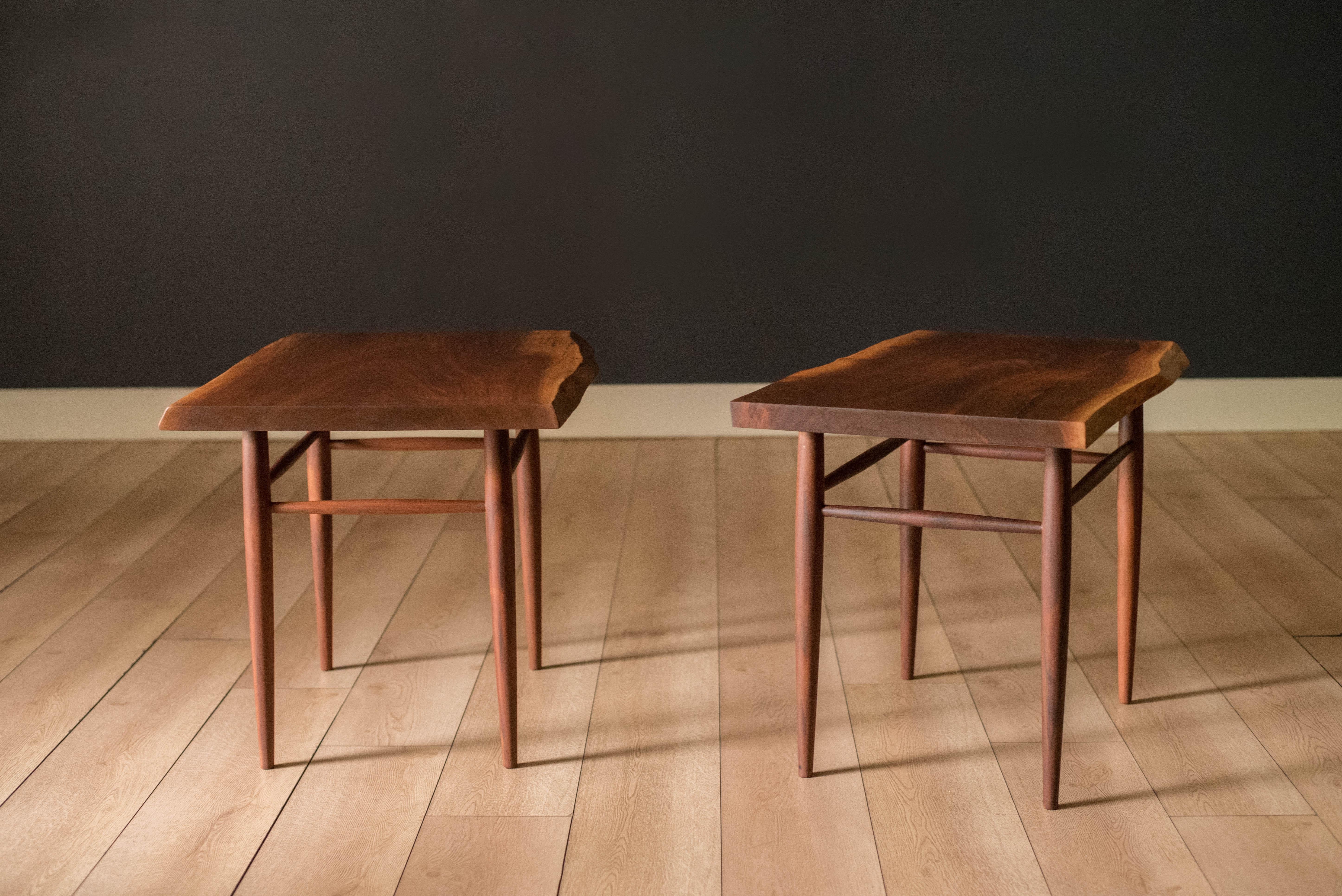 Vintage pair of side tables in solid walnut handcrafted by George Nakashima, circa 1971. This custom set features a free form table top showcasing rich grain variations supported by his signature turned leg base. Signed on the underside of the seat