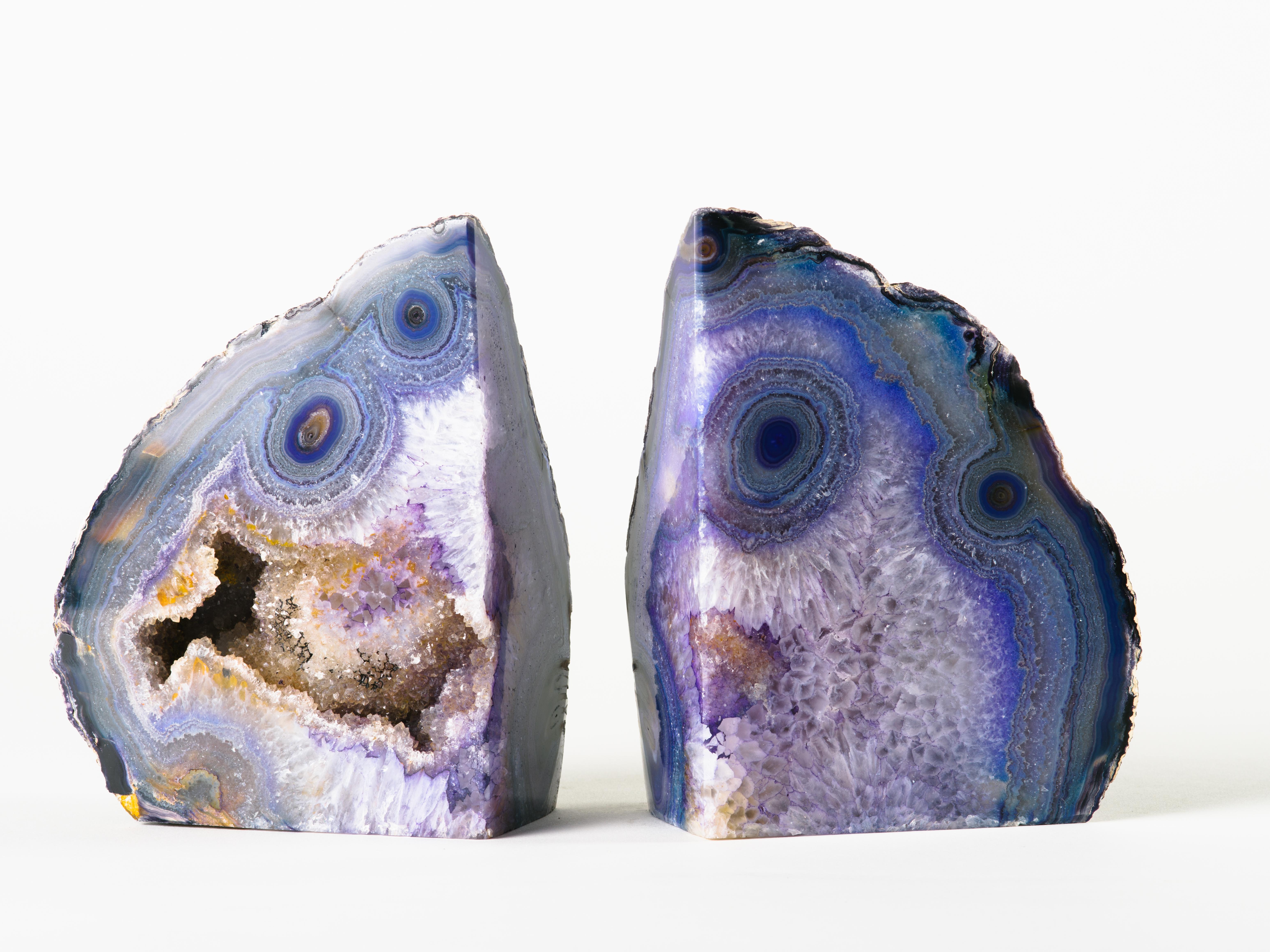 Pair of organic modern quartz crystal bookends in stunning hues of purple. Bookends feature Fine crystalline centres in varying hues of grey and amber. Features unusual circular patterns and variations of purple knots, reminiscent of wood. Bookends