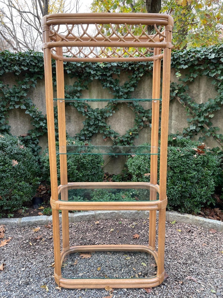 Handsome pair of Miami Modern wrapped rattan and glass shelf etageres. Each etagere has four glass shelves and decorative wrapped rattan trim.