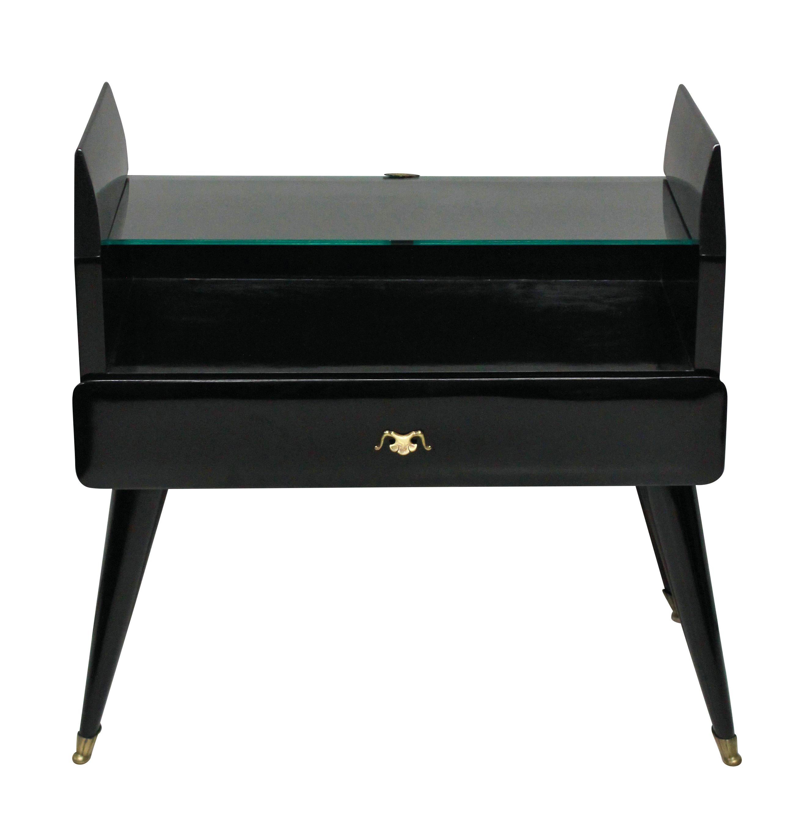 A pair of Italian black lacquered nightstands with central drawer and glass shelf, on tapering legs with brass sabot feet.

 