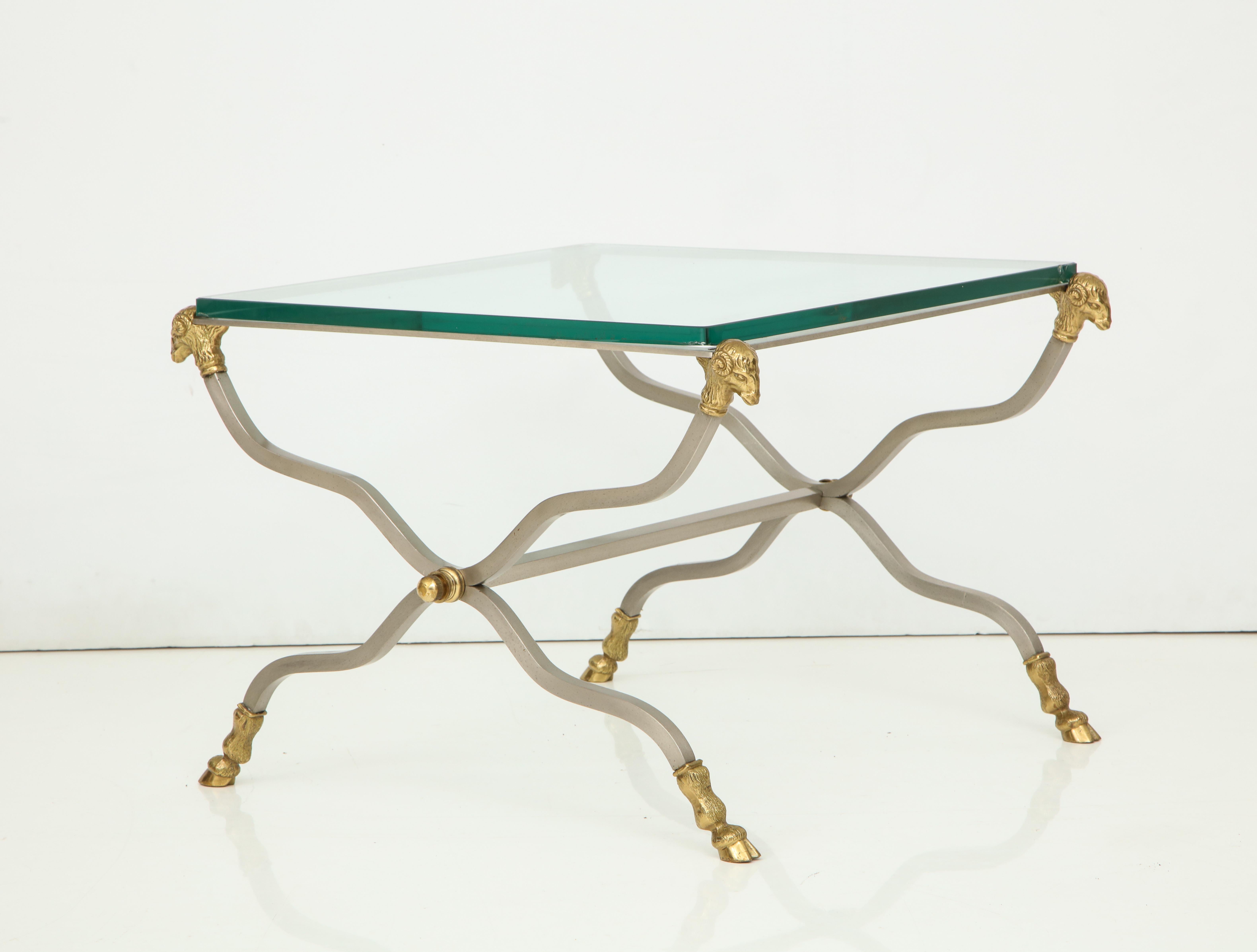 Pair of brass and glass end tables with ram's head finials and ram's feet.