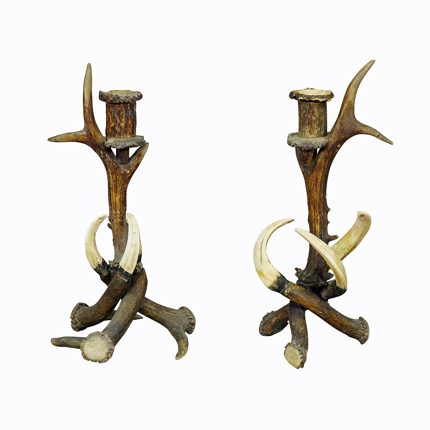 A pair of fashionable rustic candle holders, made of horns from the deer and wild boar tusks. Each features one spout made of turned antler pieces. Executed in Germany ca. 1900. These Black Forest style candle sticks would be great rustic additions