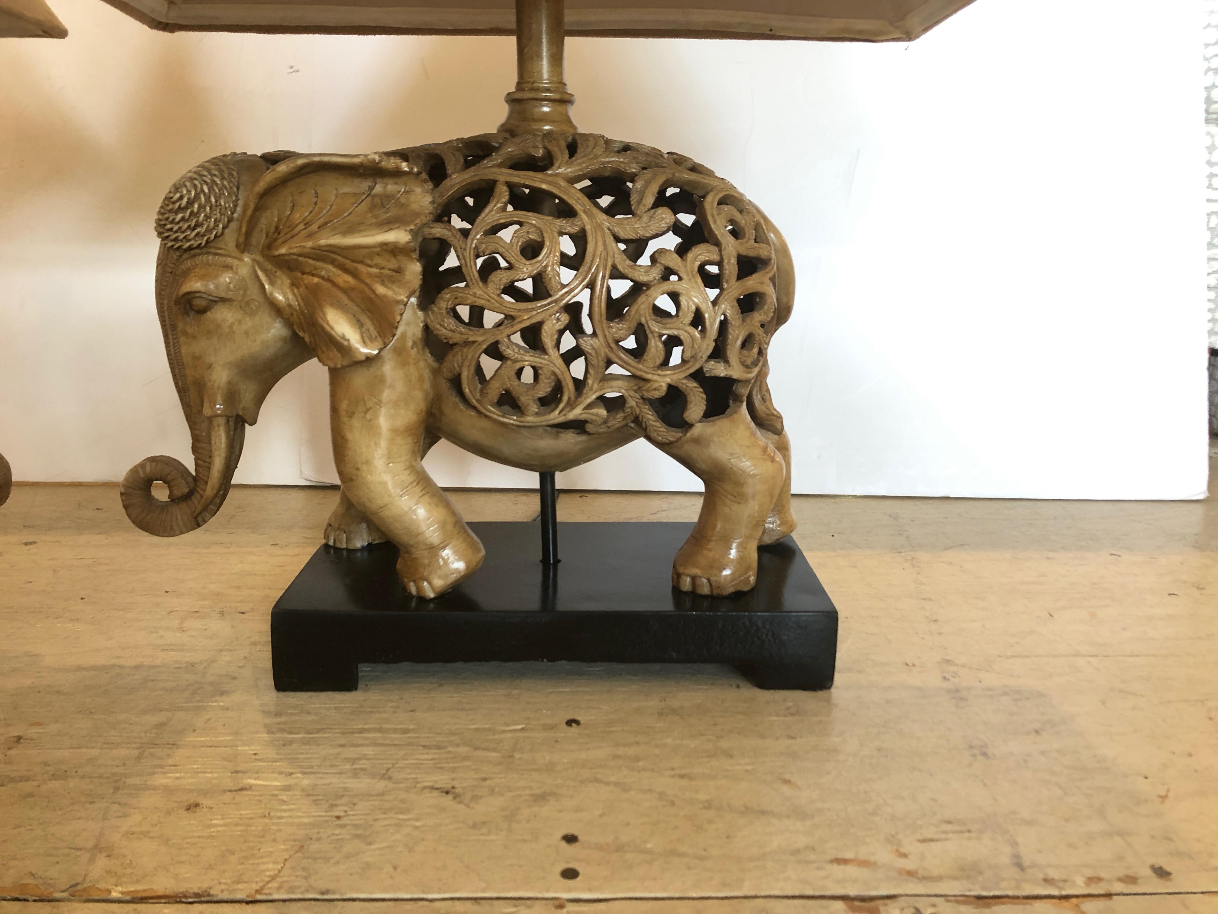 Unique pair of elephant lamps on ebonized wood bases. Lamps are a composite in a caramel color. The shades are handsome custom tan ultra suede.
