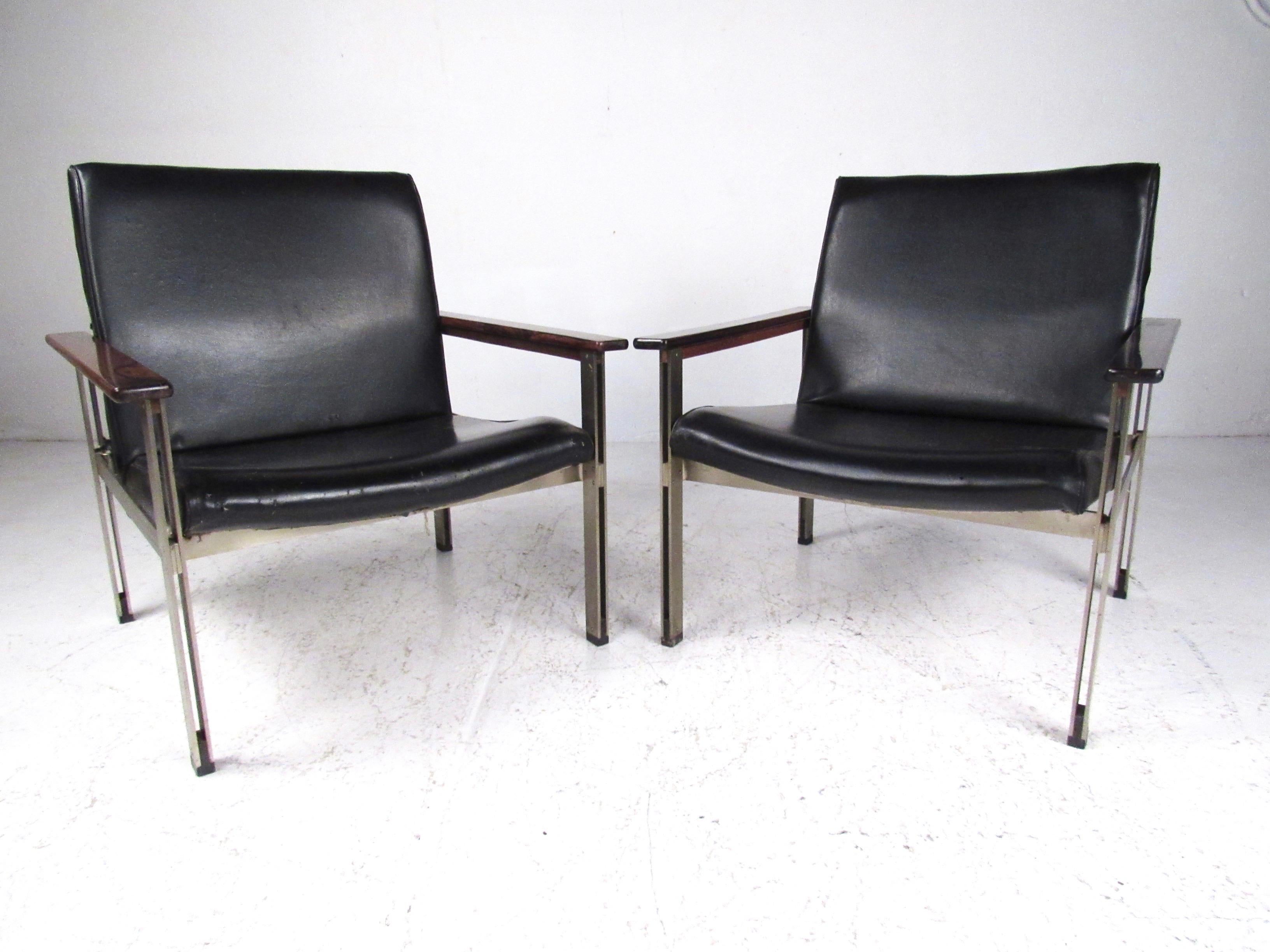 This stylish pair of matching lounge chairs features midcentury Italian modern design with Rosewood armrests and metal base frames. With eye-catching style and uniquely shaped seat backs, this vintage pair of armchairs make a distinguished yet