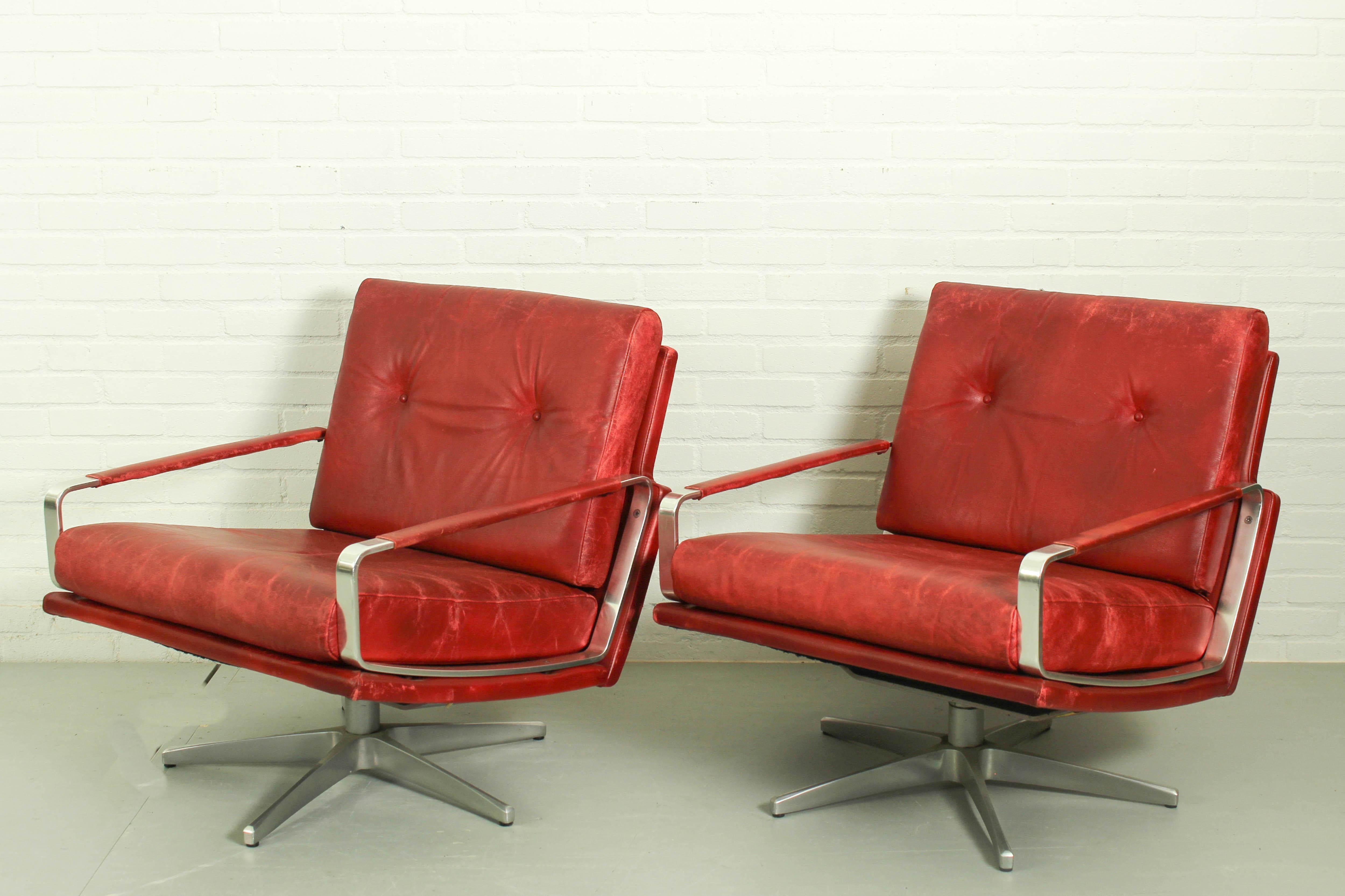 A beautiful pair of very stylish German 1960s swivel lounge chairs. The chairs are upholstered in a genuine rich dark red coloured Leather, with two removable cushions. The pieces feature a sleek low back, typical of sixties design. The chair is