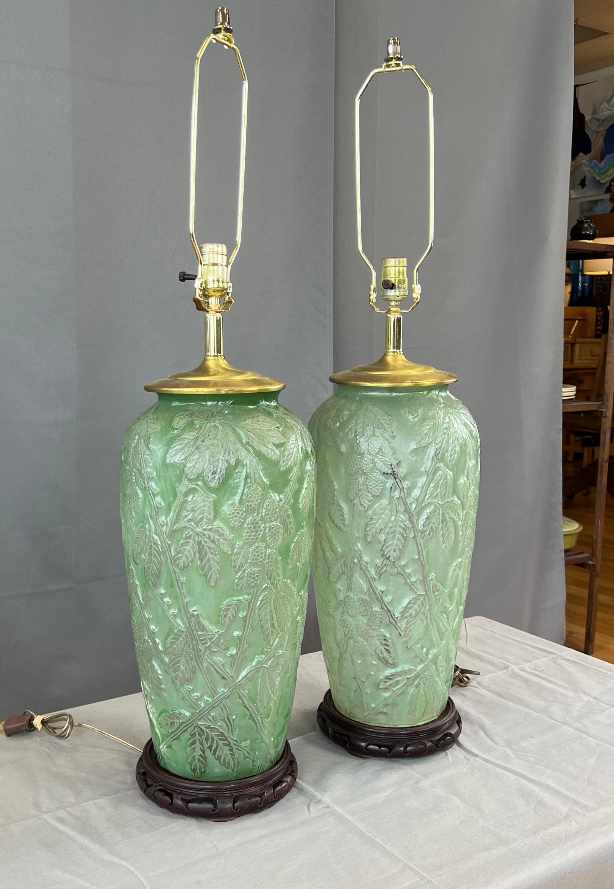 Offered here is a pair of substantial sized lamps, by the Phoenix Consolidated Glass.
Both stand on round wooden asian style bases, that are newer. Then the main body of the lamps
with a color that you could say is whitish green, then it's the two
