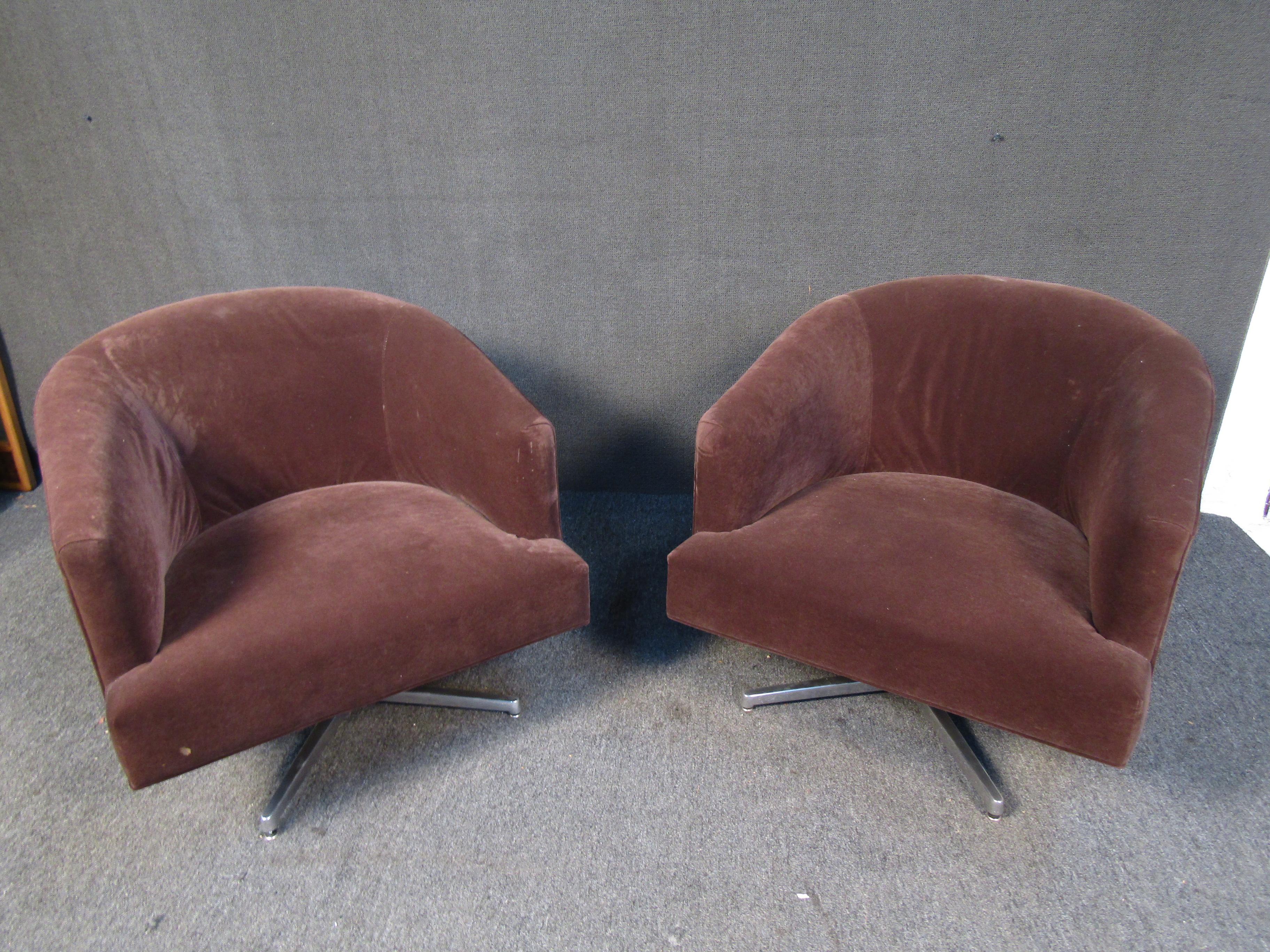 This vintage pair of large swiveling lounge chairs offer comfortable cushioning, a rich brown suede upholstery, a unique oversized design, and metal bases. Please confirm item location with seller (NY/NJ).