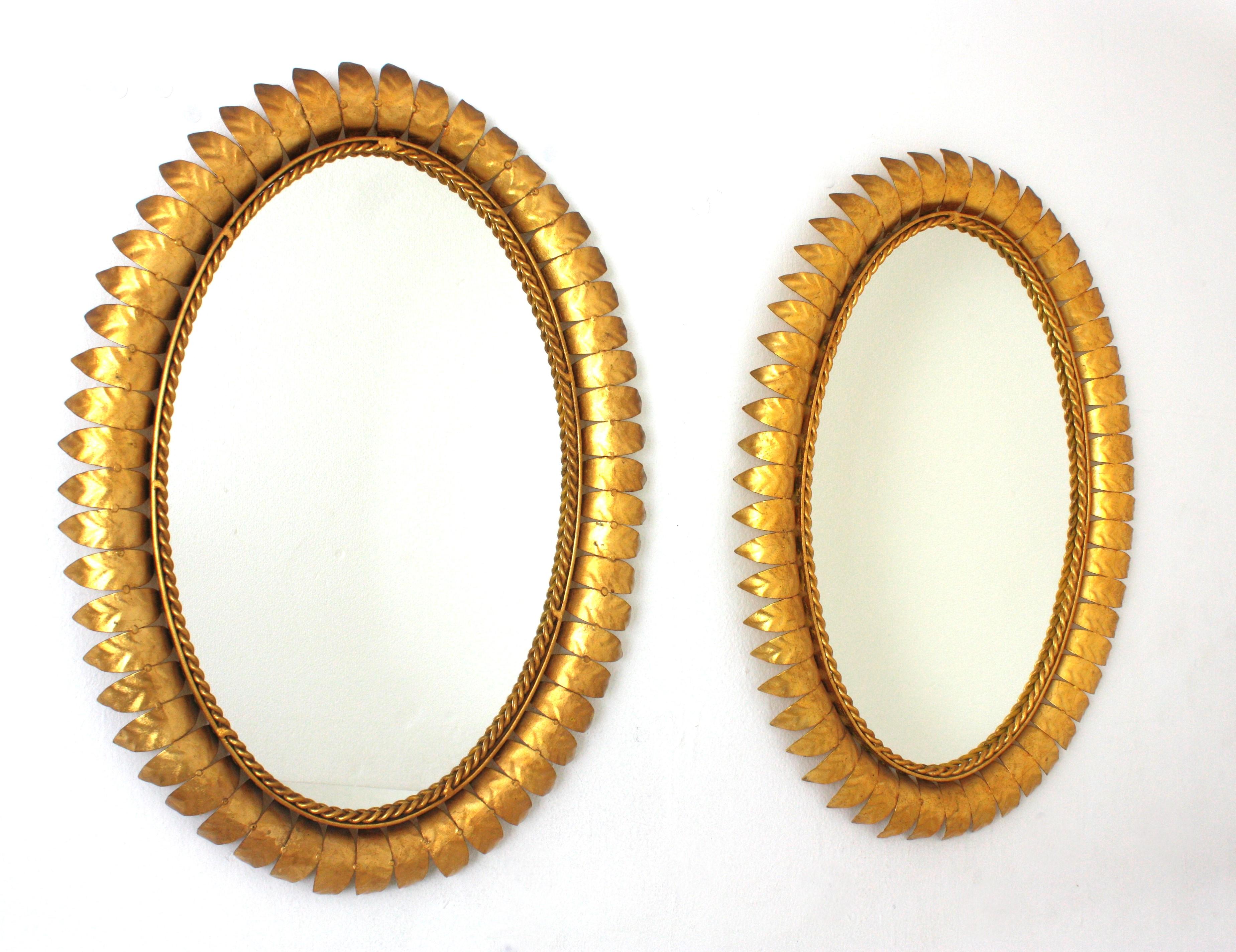 Gilt Iron Oval Sunburst Mirrors, Pair
Pair of Mid-Century Modern iron sunburst oval wall mirrors with leafed frames and gold leaf finish, Spain, 1950s.
These highly decorative leafed sunburst mirrors have a nice patina showing their original gold