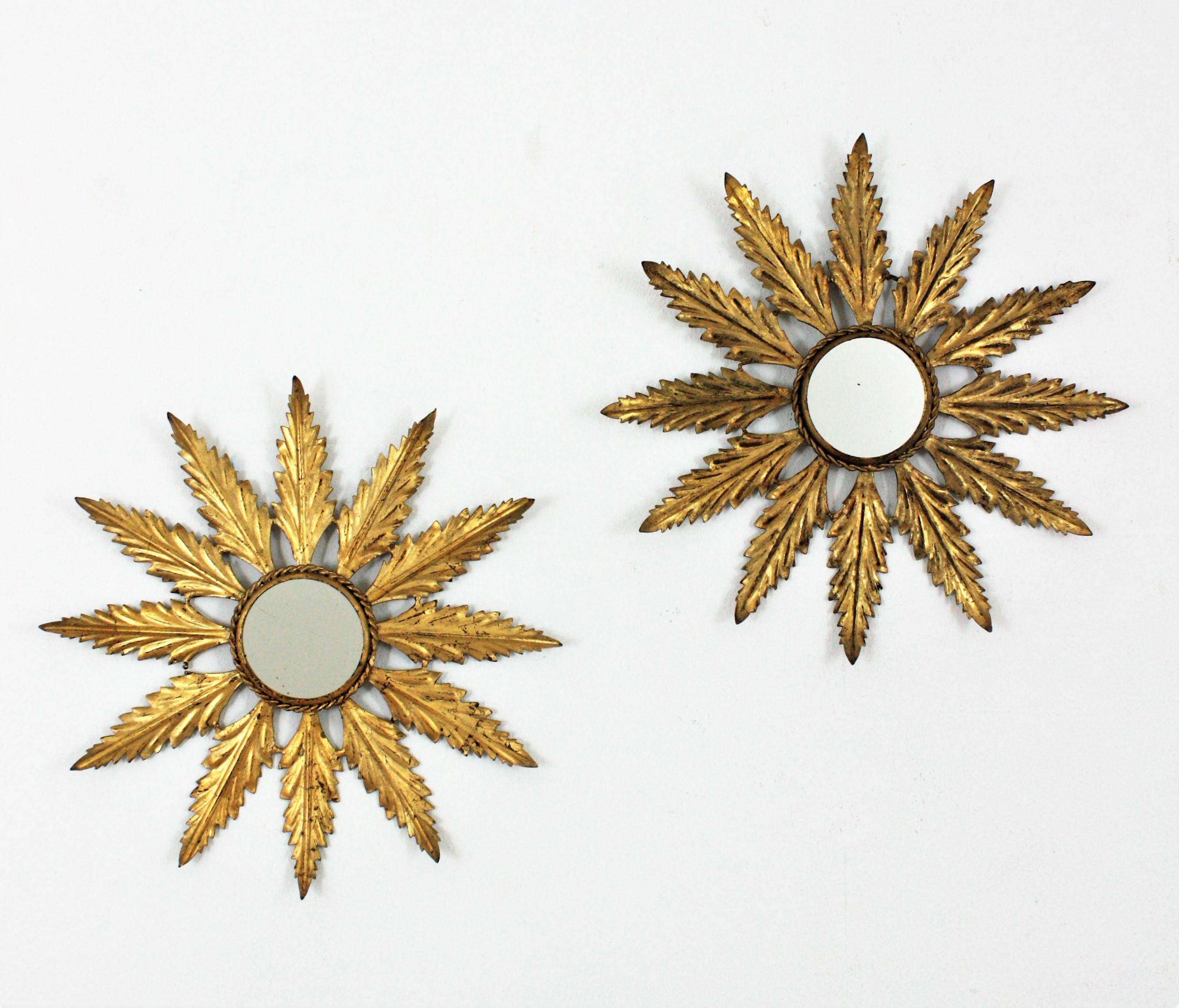 Eye-catching pair of hand-hammered gilt iron leafed sunburst mirrors in small size, Spain, 1940s-1950s.
The leafed frames in gilt iron finished with gold leaf have a nice aged patina. The small size and the clean design mark the difference in these