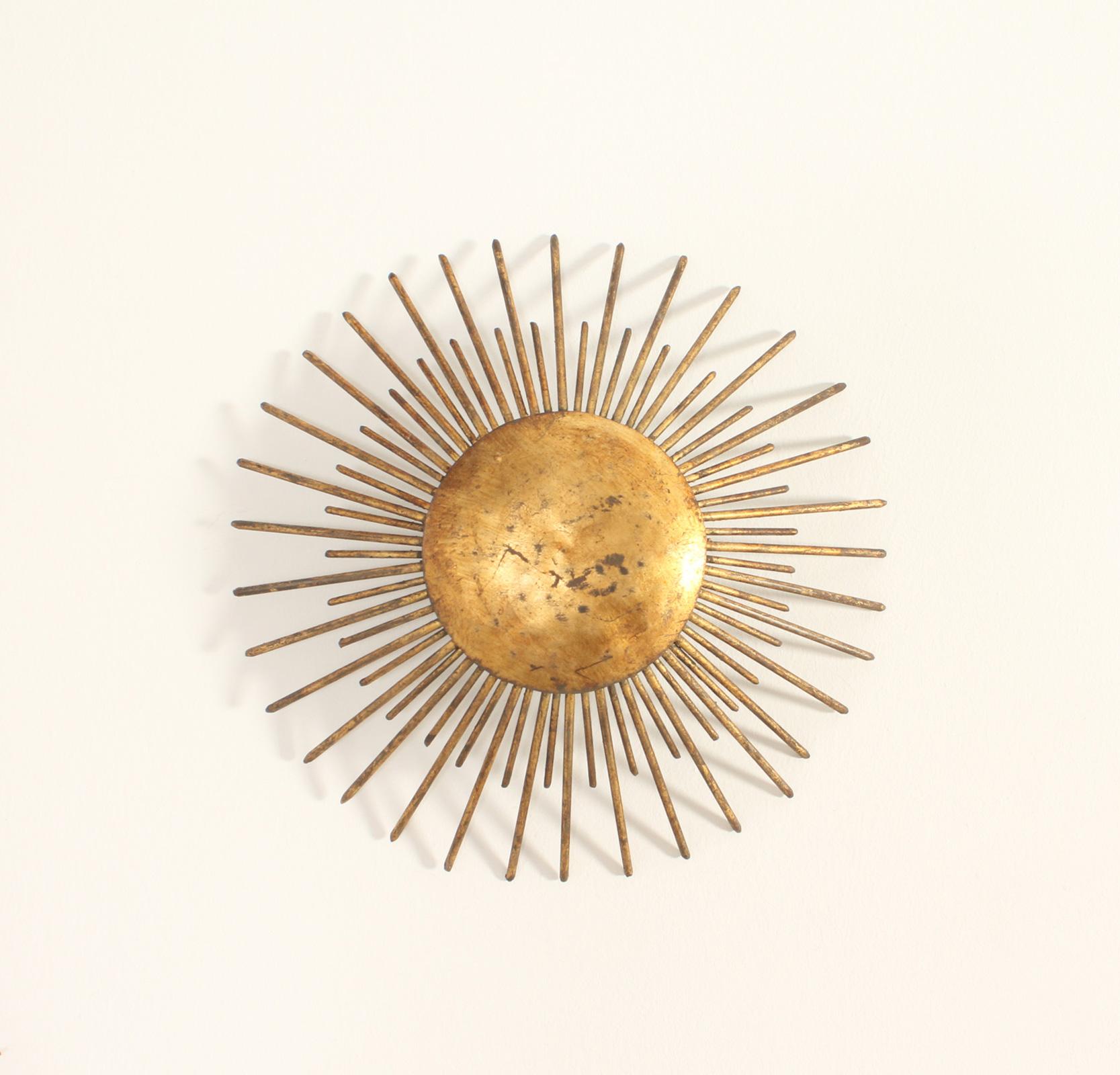 Pair of sunburst wall or ceiling lamps from 1940's, France. Hand hammered gilt forged iron with two bulbs in each lamp, they can be used as a ceiling or wall lamps.
