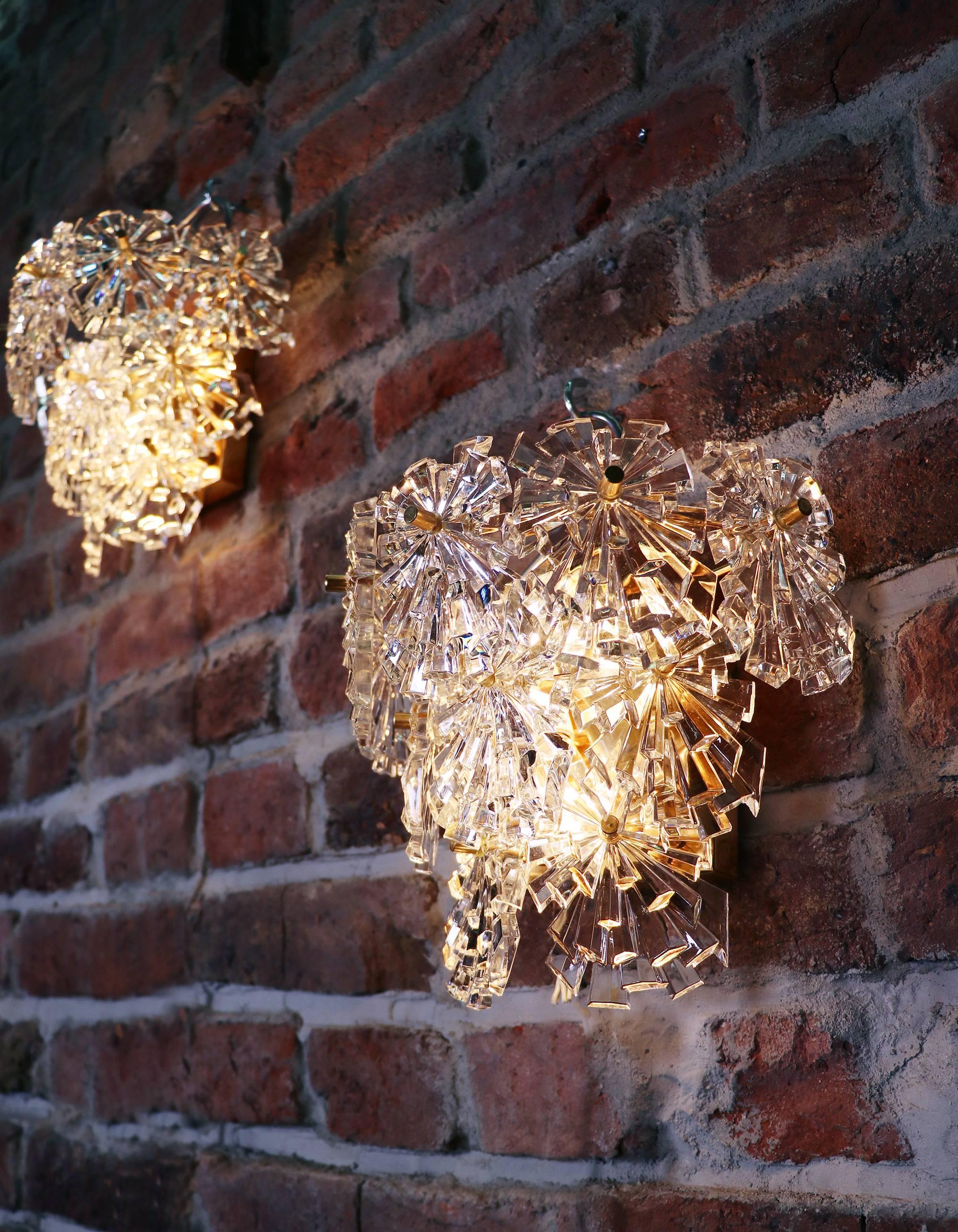 Elegant pair of starburst crystal glass wall sconces, each with ten faceted crystals mounted on gold-plated brass frame. Star-shaped crystal glass resembles flowers. With this light you make a clear statement in your interior design. Sconces