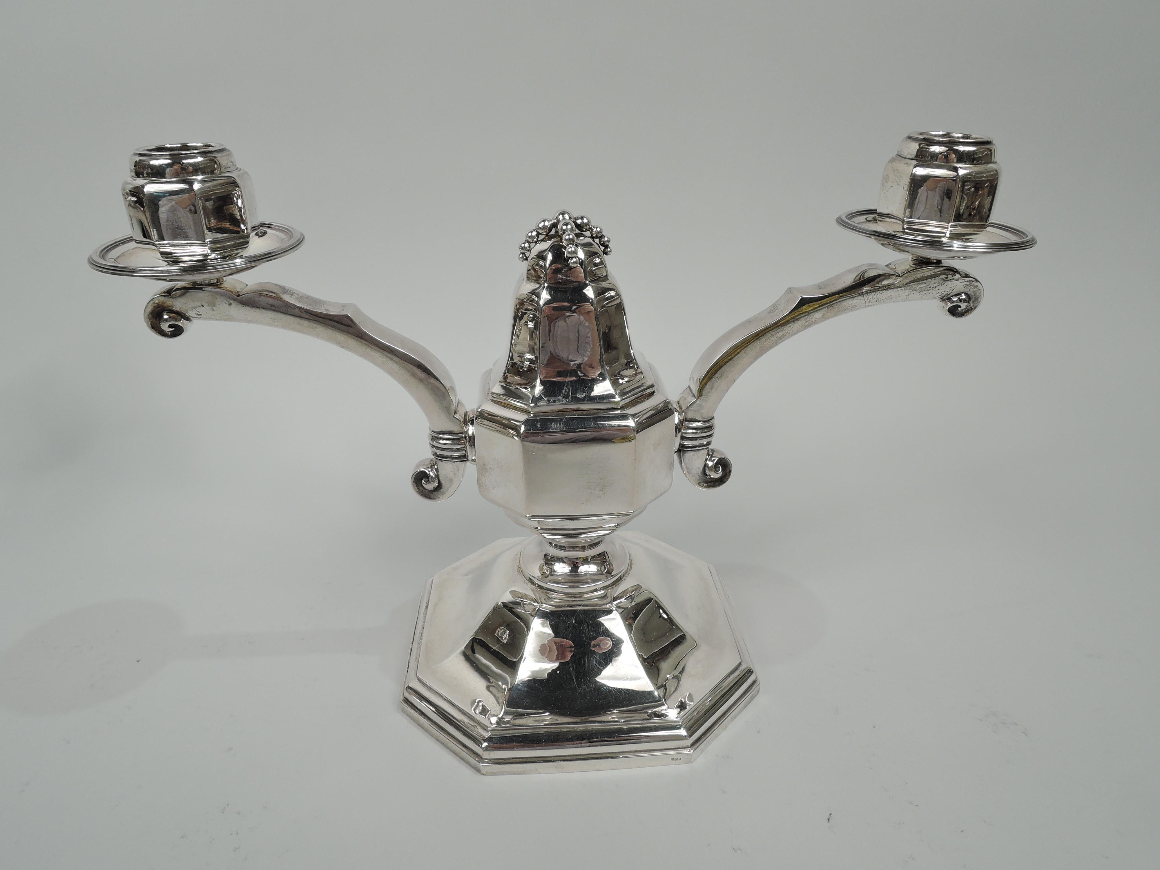 Pair of super stylish Art Deco Classical 950 silver 2-light candelabra, ca 1930. Each: Broad and faceted. Two scrolled arms with volute terminals and single socket on reeded wax pan bracketed to baluster with beading draped over top; raised foot.