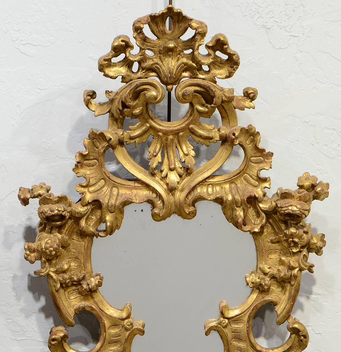 This high quality pair of carved giltwood Baroque mirrors features exquisitely carved open work frames with scrolls leaf work and flowers centering mirror glass of a later date. The style is earlier than the later Rococo style of Louis XV but