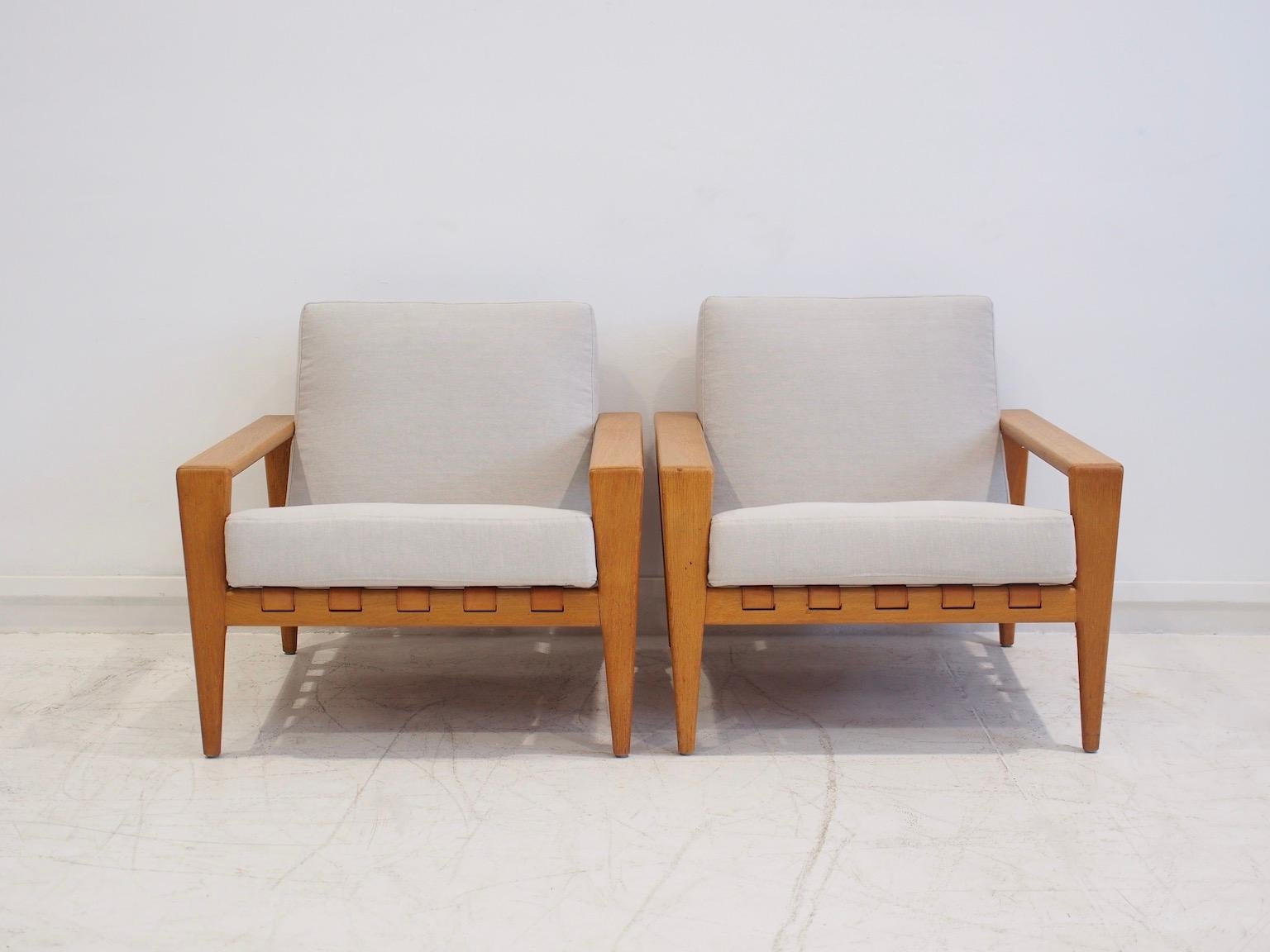 Pair of easy chairs, model Bodö, designed in 1957 by Svante Skogh. Made by AB Hjertquist & Co in Nässjö, Sweden. Frame in oak, leather saddle seat, recently reupholstered cushions in light grey fabric. These armchairs with their clean lines and
