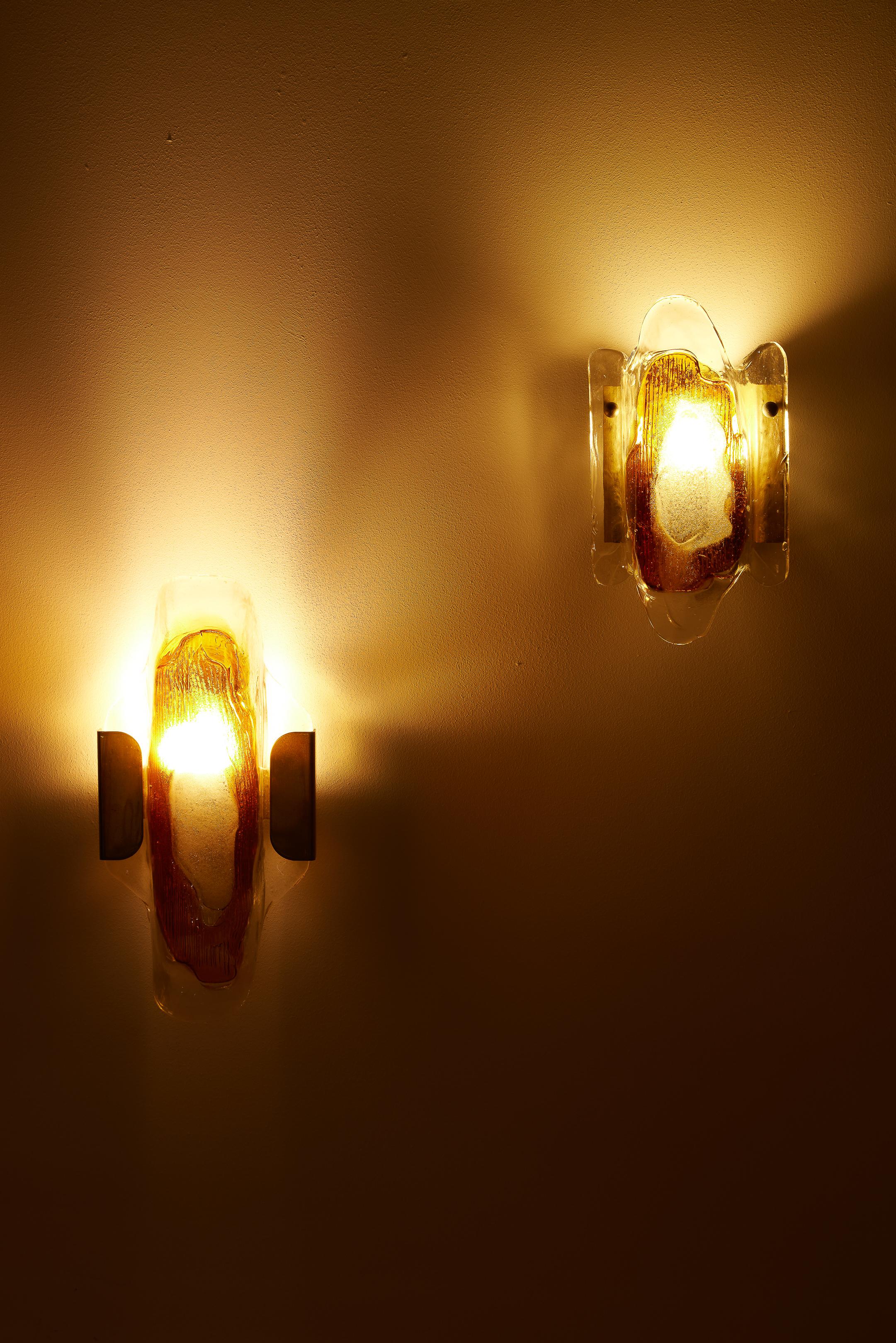 Pair of wall lamps by Danish designer Svend Aage Holm Sørensen (1913-2004), from the 1950s. The diffuser is made of transparent glass with an orange geometric pattern in the center. The structure is in golden brass. In very good