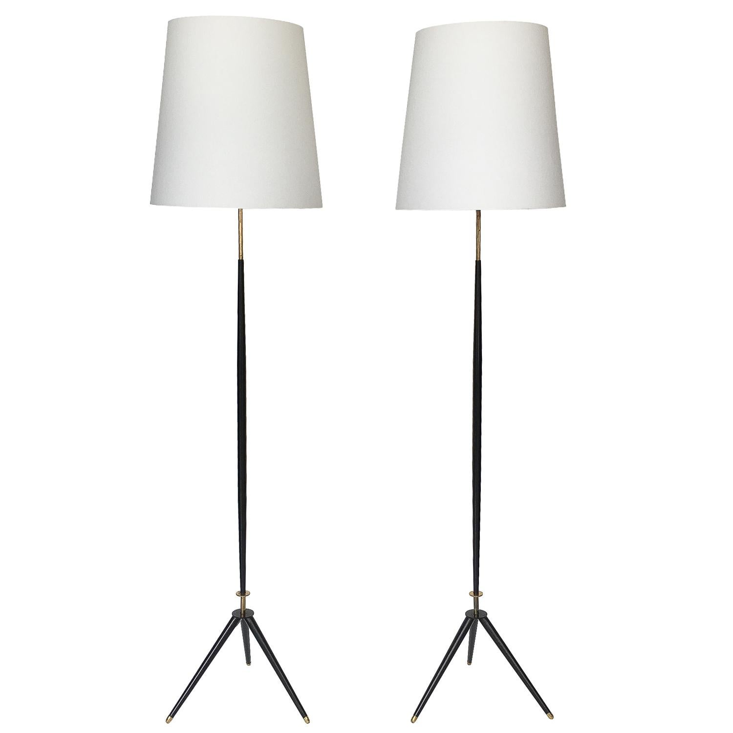 Pair of elegant floor lamps by Svend Aage Holm Sorensen. Manufactured by Holm Sorensen & Co. Denmark, circa 1950s. Striking tripod legs that feel almost Italian rather than Scandinavian! These lamps feature black enameled steel supports and tripod
