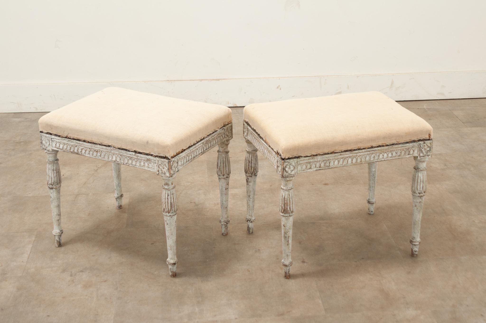 A Swedish pair of Louis XVI style benches made in the 1700’s. These classically styled benches have a neutral colored top cushion filled with horsehair, ready for a custom upholstery. The frames have hand-carved rosettes  in each corner and other