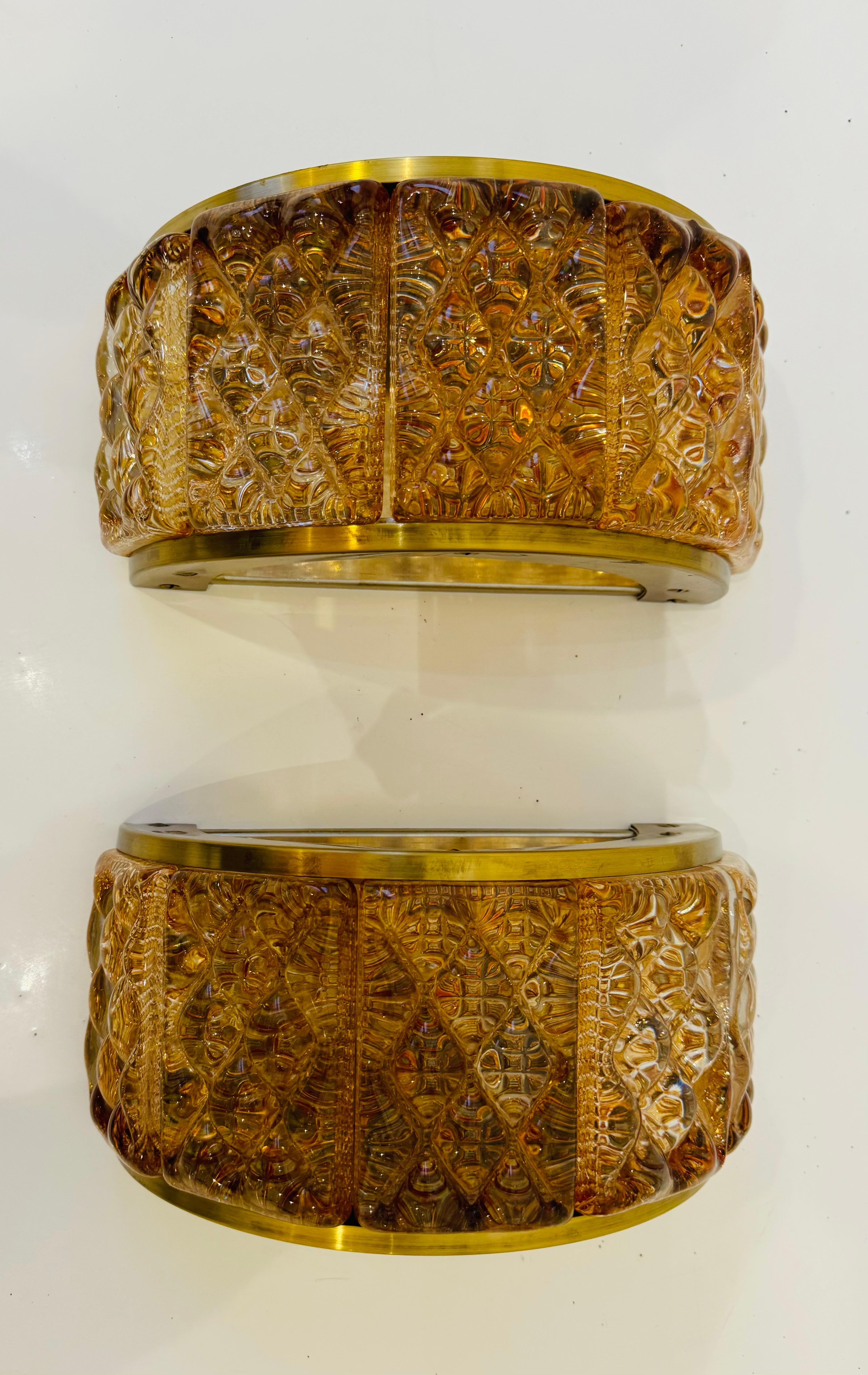 Coppia di appliques svedesi della metà del secolo scorso composte da cornici in ottone satinato e paralumi in vetro tagliato a cuscino color ambra. Prese a candelabro. Ricablata. Un lato è aperto per emettere luce e calore. Può essere montato in