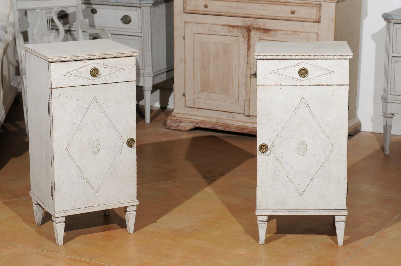 A pair of Swedish Gustavian style nightstand tables from the 19th century, with drawers, doors and diamond motifs. Created in Sweden during the 19th century, each of this pair of bedside tables features a rectangular top sitting above a dentil-style