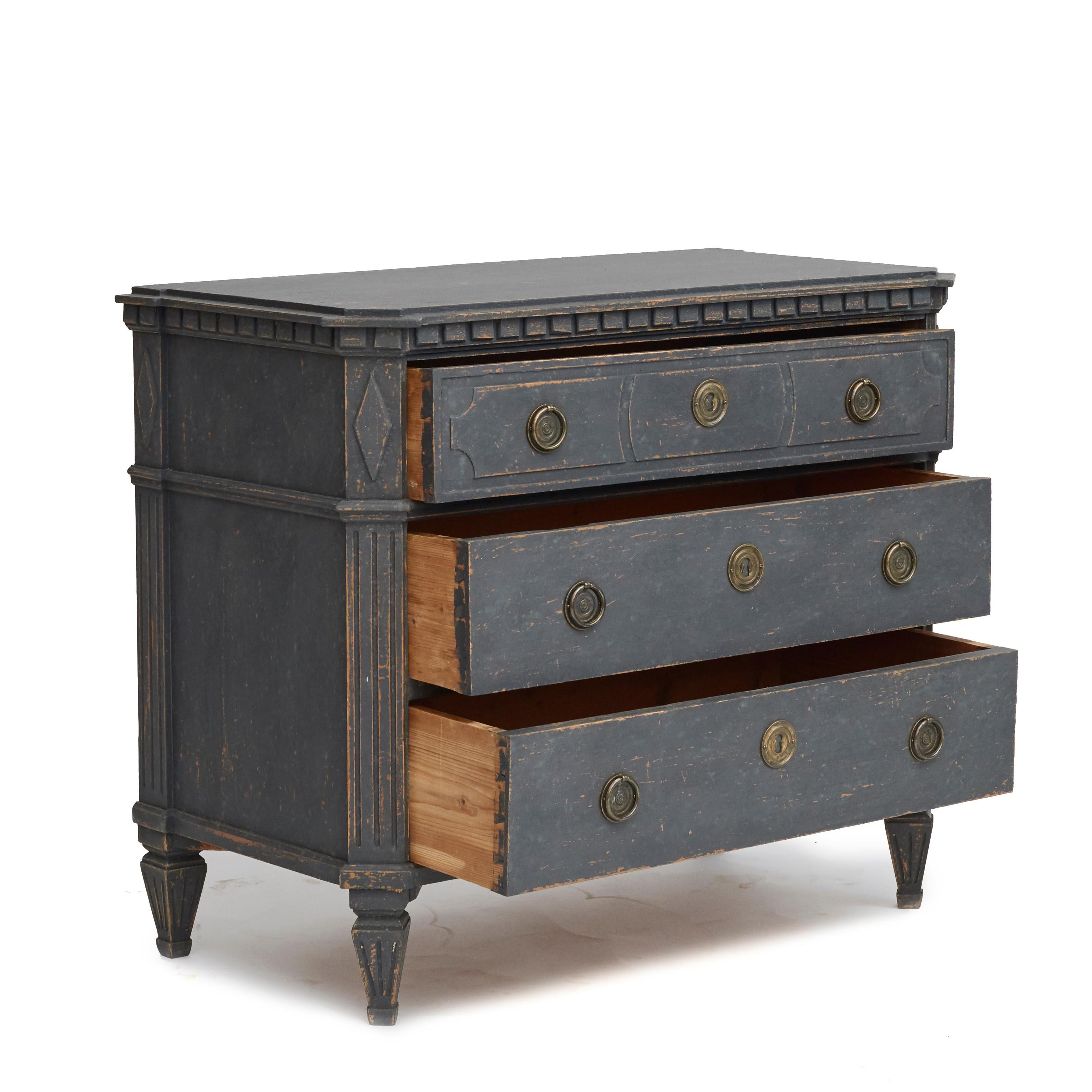 A pair of Swedish Gustavian style graphite grey painted three-drawer commodes dating from the 19th century.
Each chest features a rectangular top with canted corners in the front, sitting above a delicate dentil molding running on three