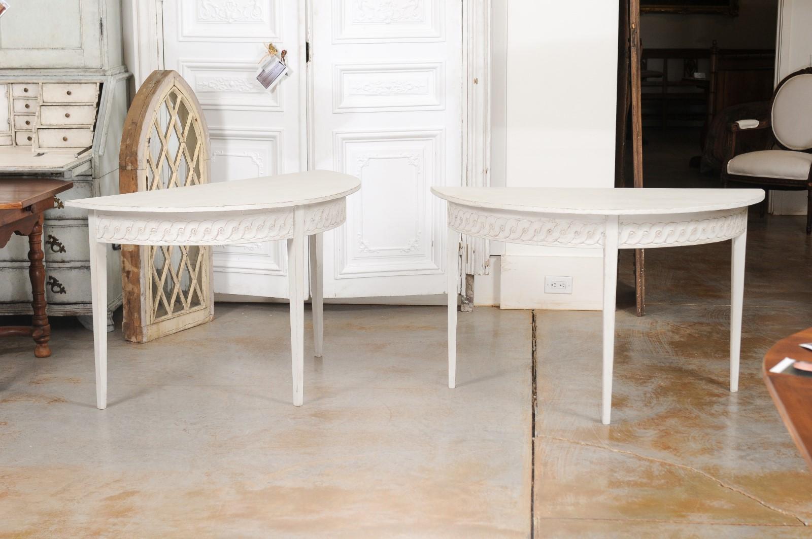 A pair of Swedish neoclassical style demilune console tables from the 19th century, with guilloche motifs and tapered legs. Created in Sweden during the 19th century, each of this pair of demilunes features a semi-circular top sitting above an apron