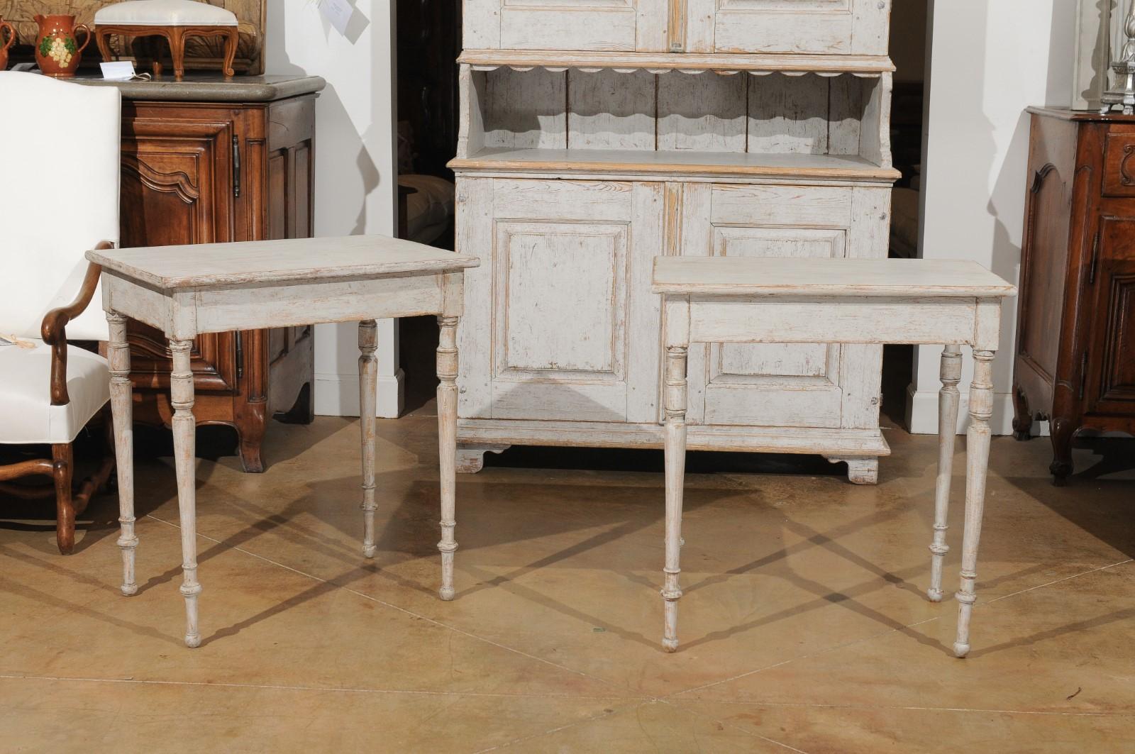 A pair of Swedish painted tables from the 19th century, with turned legs and distressed finish. Created in Sweden during the 19th century, each of this pair of painted tables features a rectangular top sitting above a simple apron. Raised on four