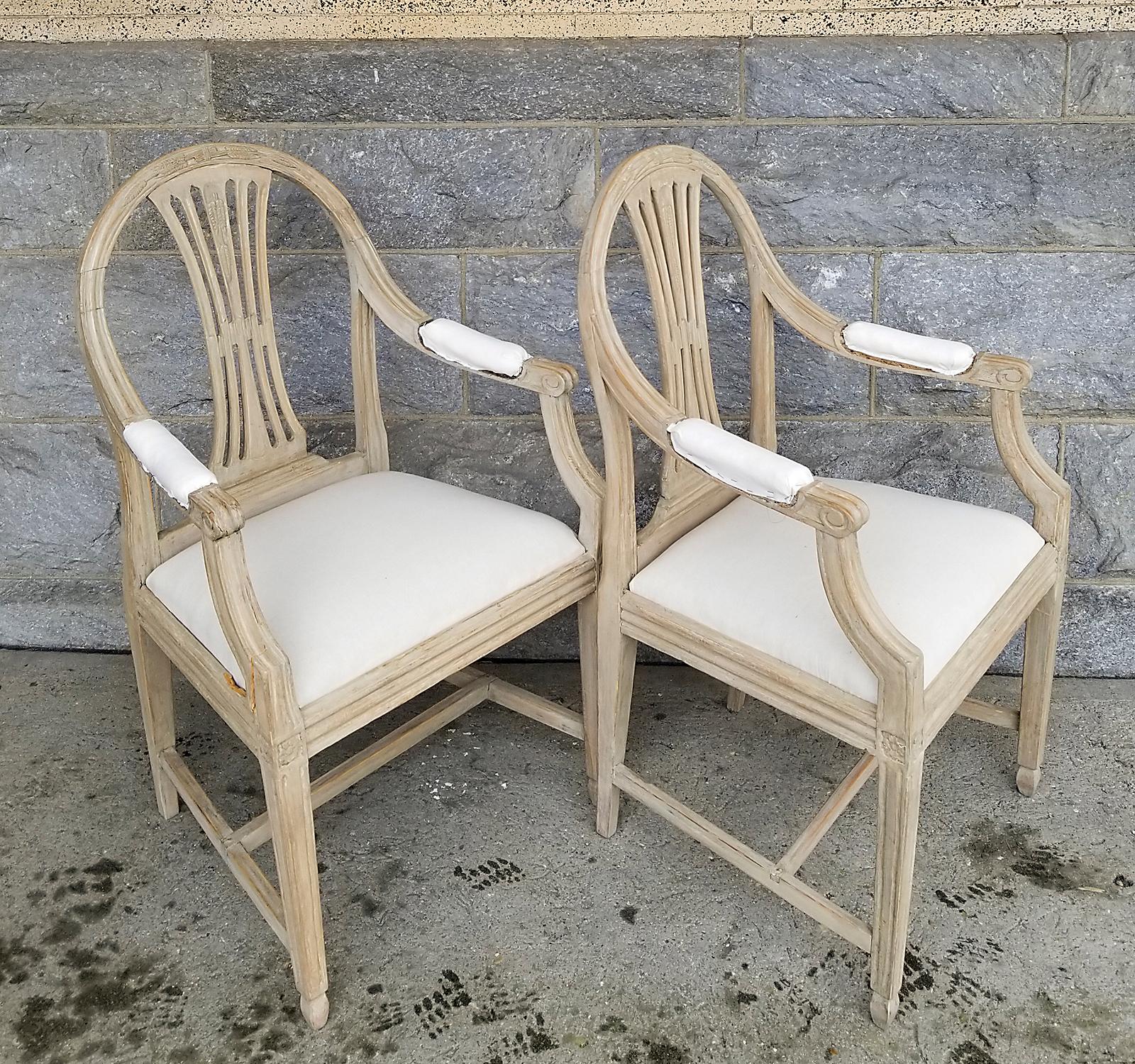 Pair of period Gustavian armchairs, Sweden circa 1800, with rounded backs and upholstered seats. The pierced splats and top rails have carvings of wheat, a symbol of prosperity and abundance. Padded armrests, square legs, and H-shaped stretchers. No