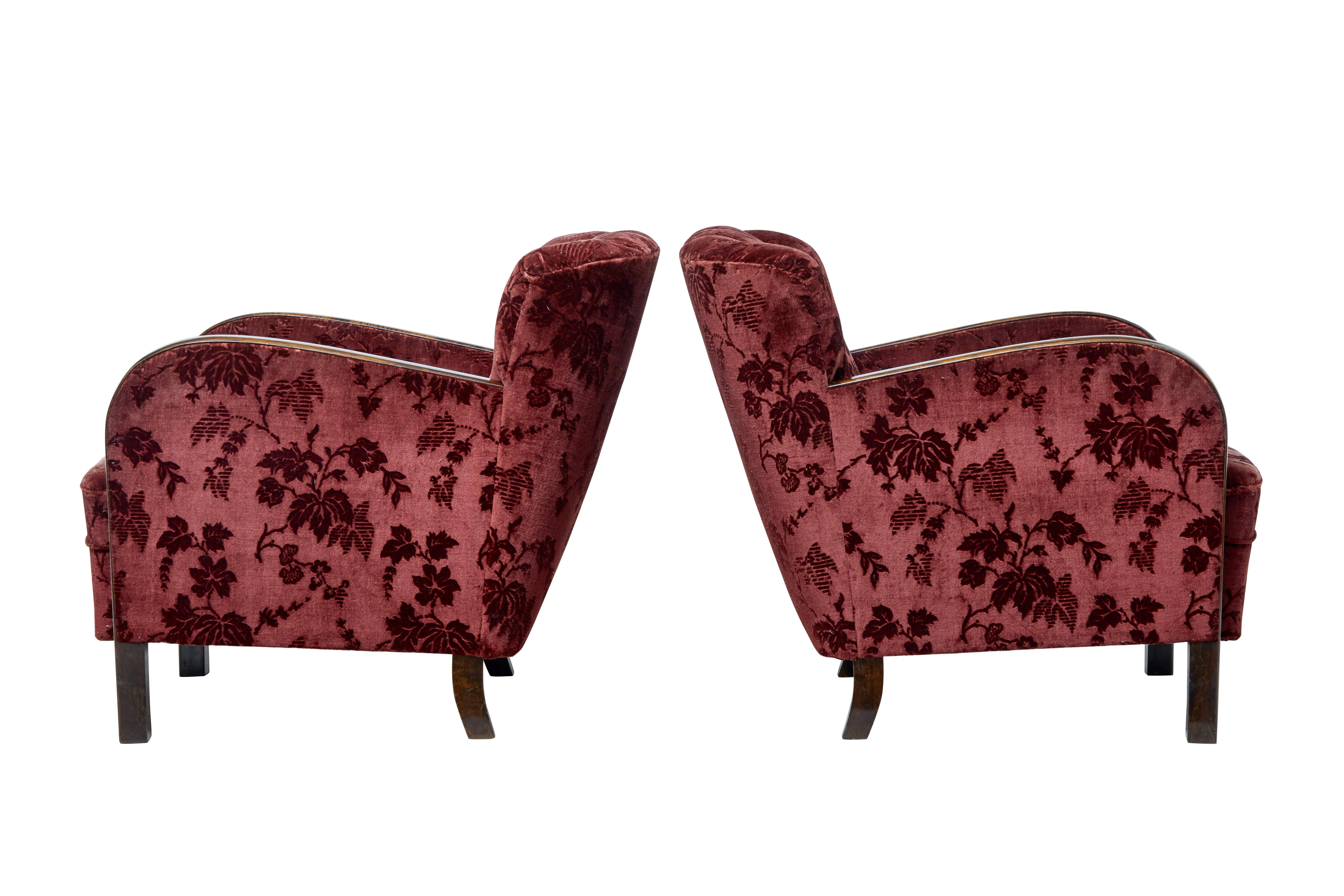Pair of late Art Deco period armchairs, circa 1940.

Shaped shell back design, typical continuous flowing arm which is presented in a dark stained birch.

Covered backs which allows these chairs to be free standing.

Original velvet covering