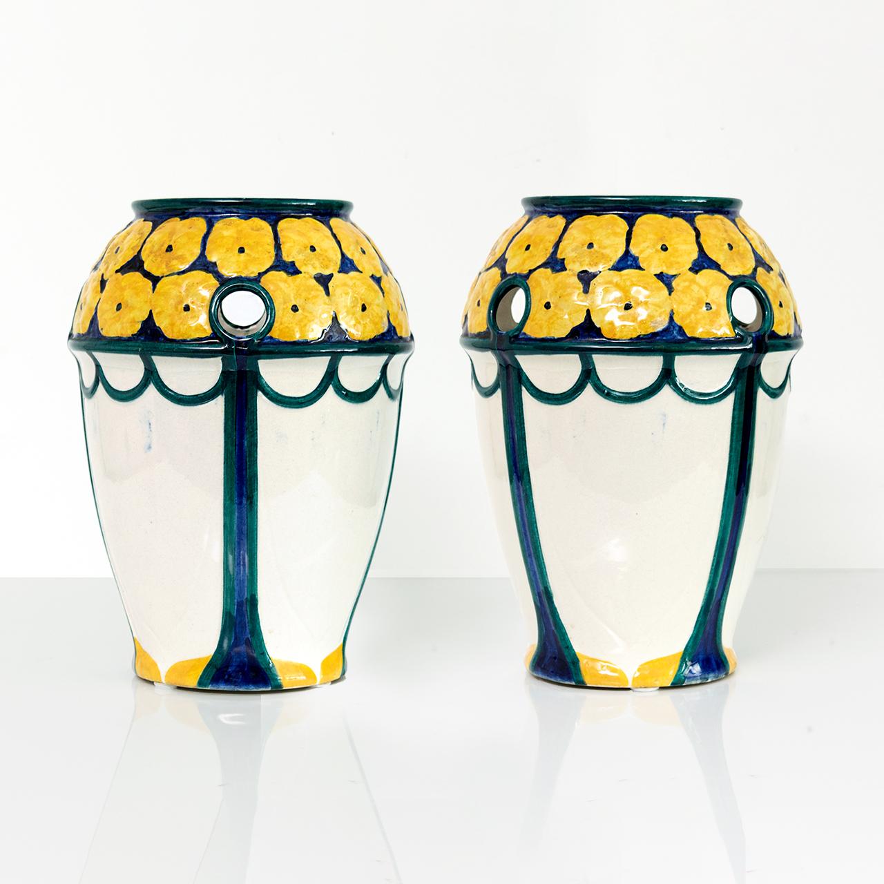 Pair of Swedish Art Nouveau period vases with a crown of yellow flowers on a deep blue ground. The vases has small round openings along the top. Designed by Alf Wallander made by Rorstrand, circa 1910. 

Measures: Height 10.75”.
