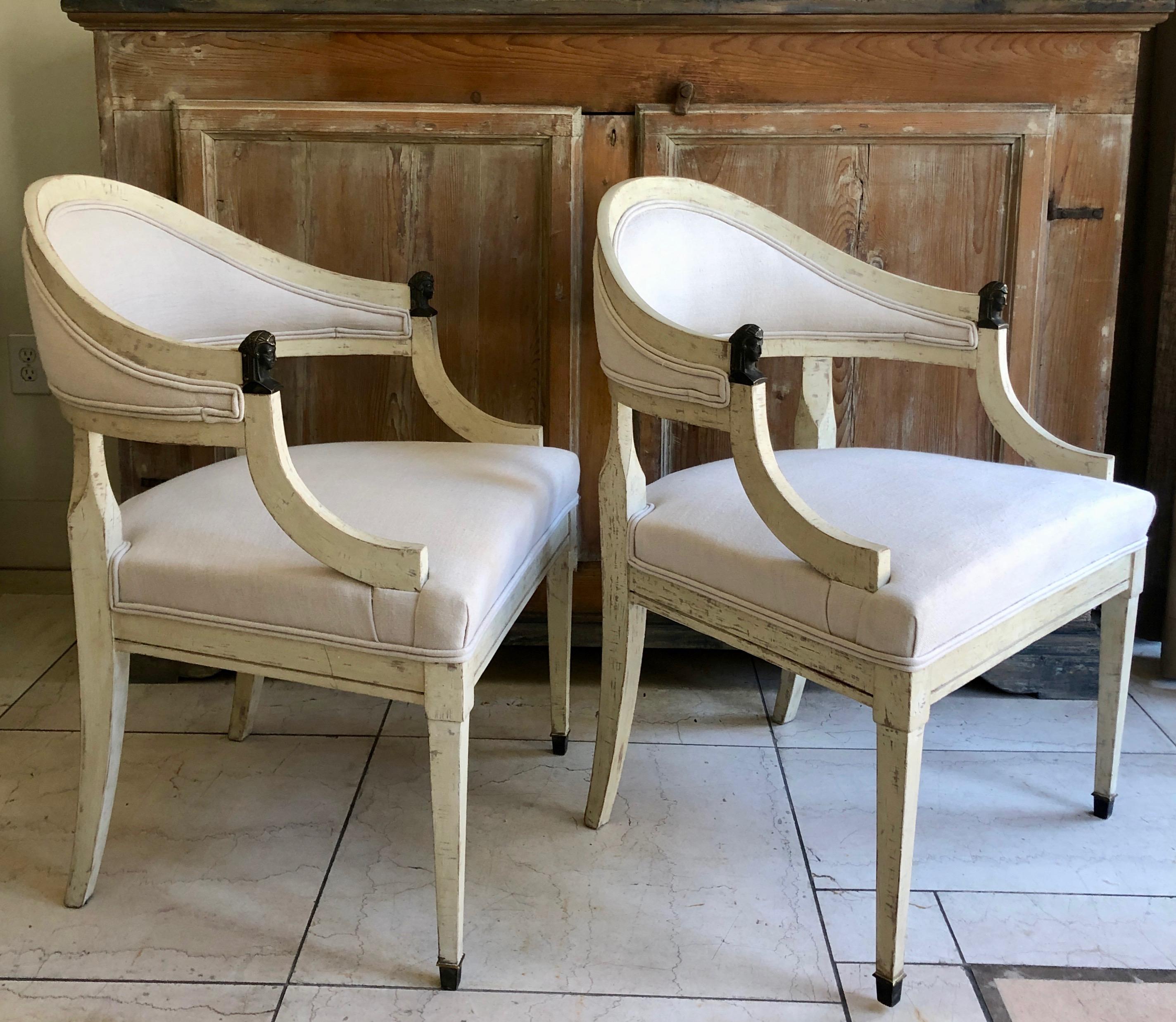 Pair of barrel back chairs, Sweden circa 1890, with rounded form, bronze figural pharaoh head details on handrest and slender tapered legs with bronze fittings. Original worn cream/ white paint finish and new linen upholstery.
More than ever, we